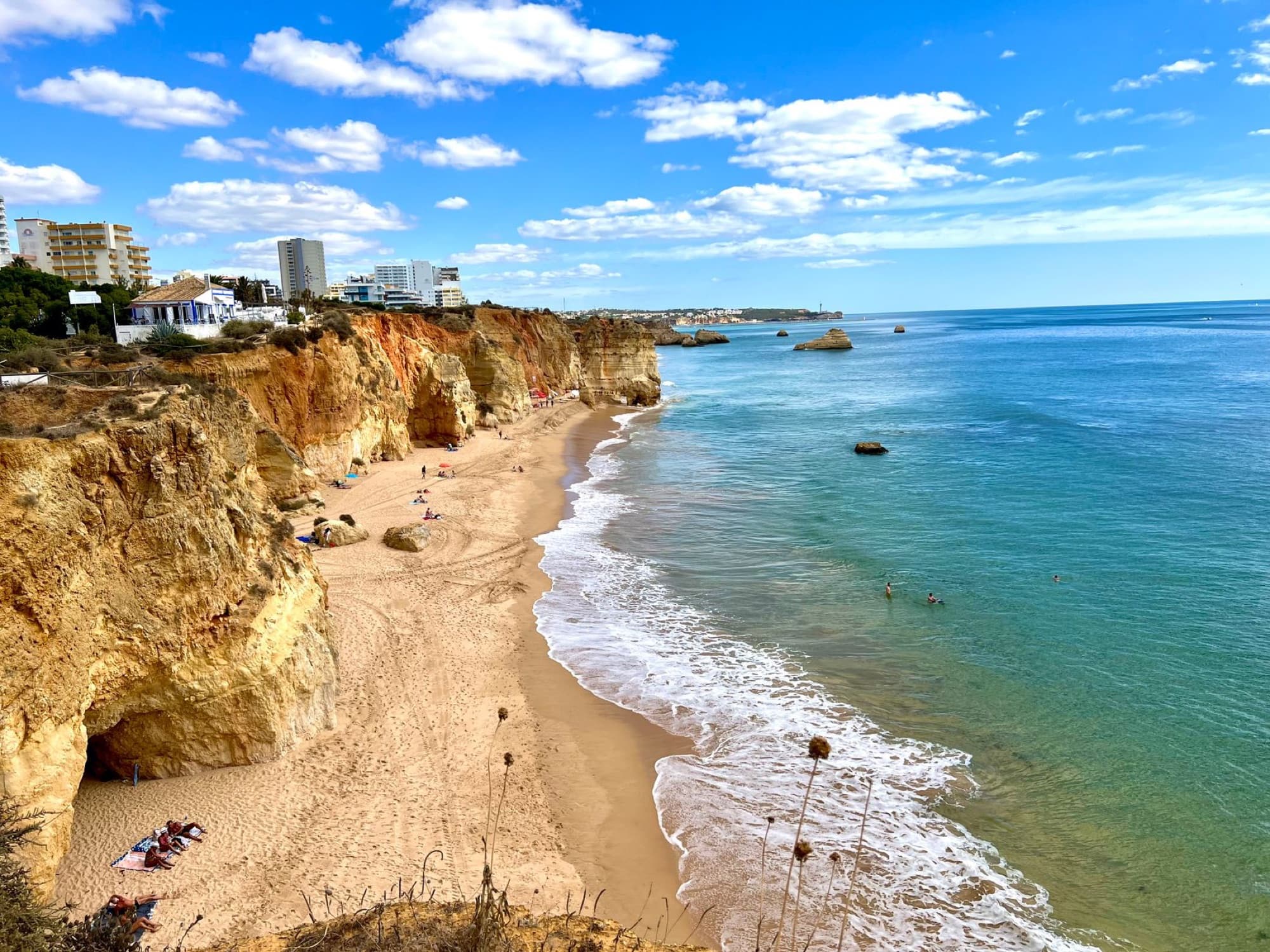 Scenic view of Algarve coast with cliffs and sandy beach under a clear blue sky.