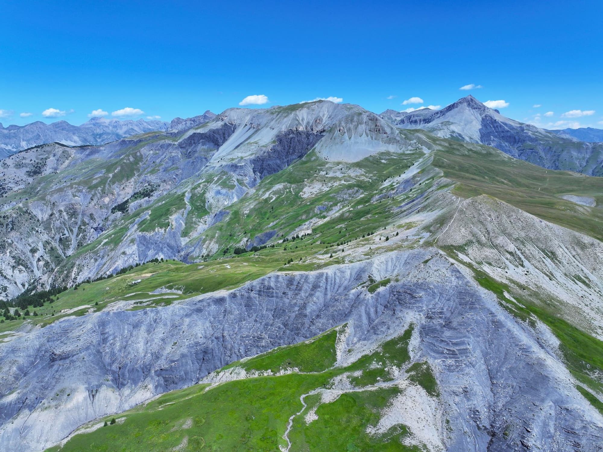 Dramatic aerial view of the Alpine mountains in Mercantour National Park, showing vibrant greenery and rugged peaks.