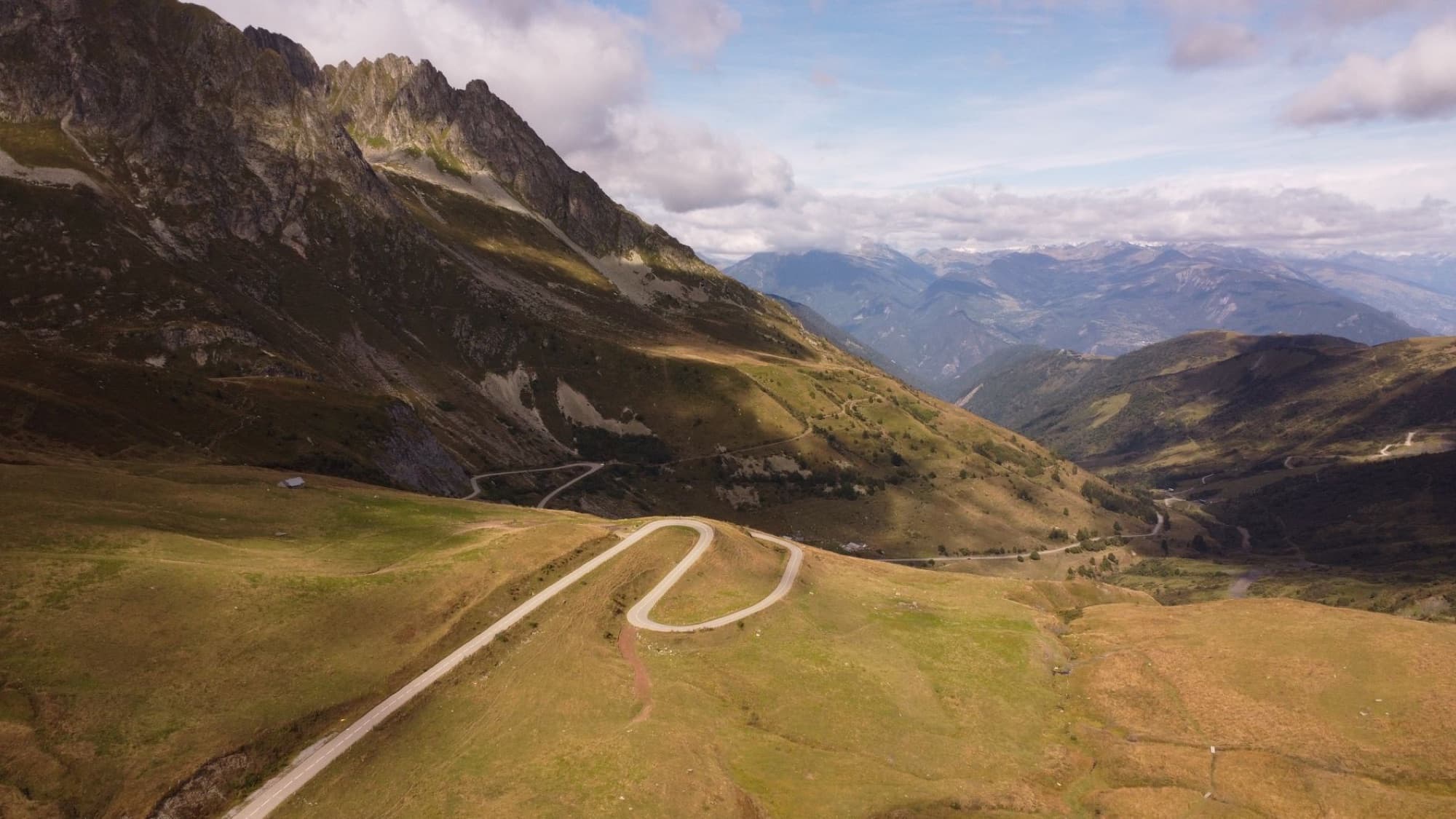 A scenic aerial shot of a winding mountain road in the French Alps, showcasing natural beauty.