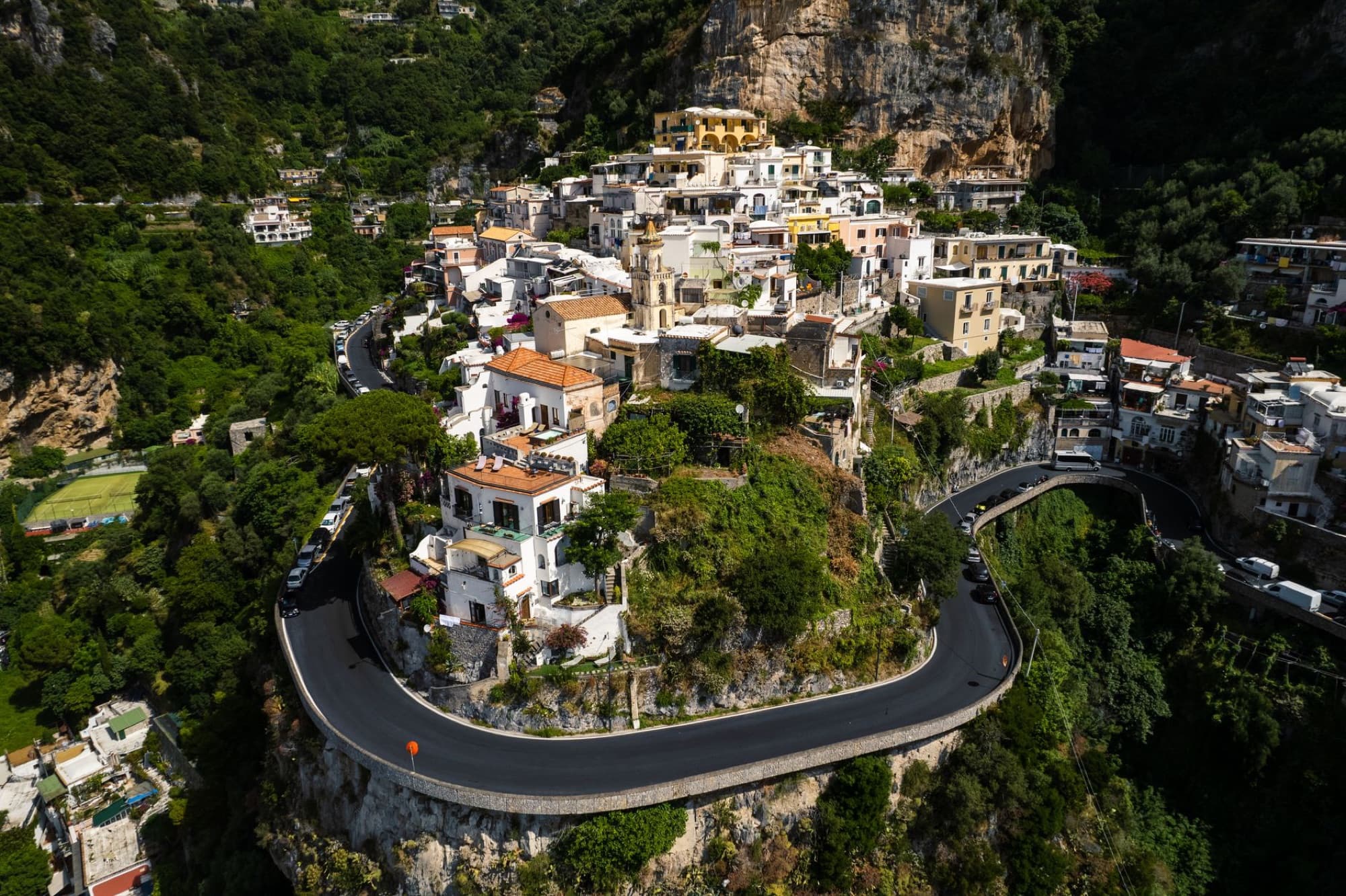 Stunning aerial view of a picturesque town on the Amalfi Coast with winding roads and lush greenery.