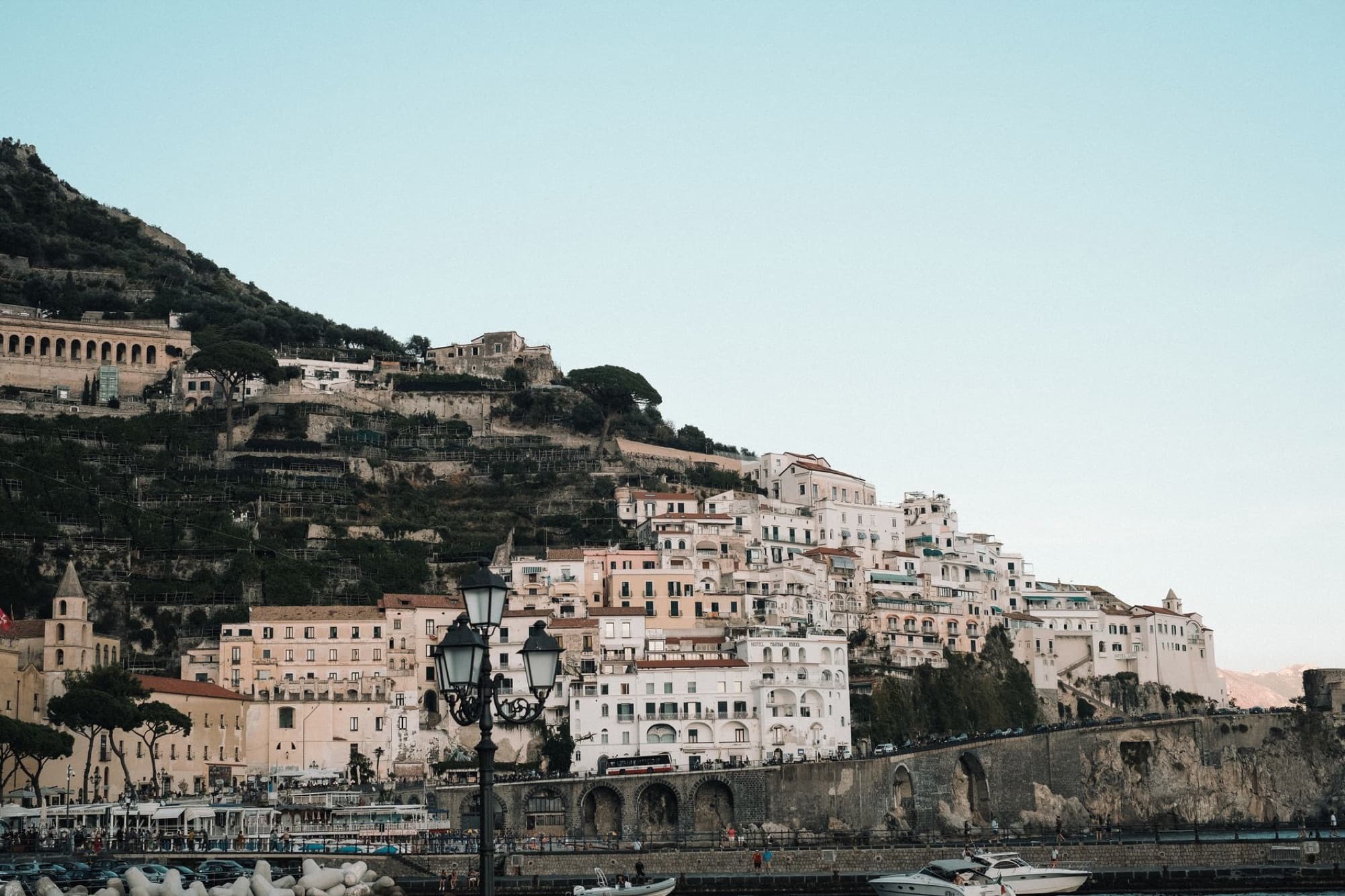 A picturesque view of a coastal town on the Amalfi Coast with hillside buildings and boats in the harbor.