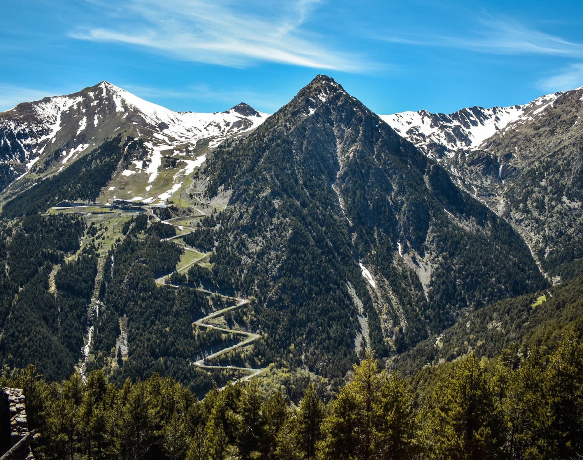 A stunning aerial view of snow-capped mountains in Andorra under a clear blue sky, showcasing nature's beauty.