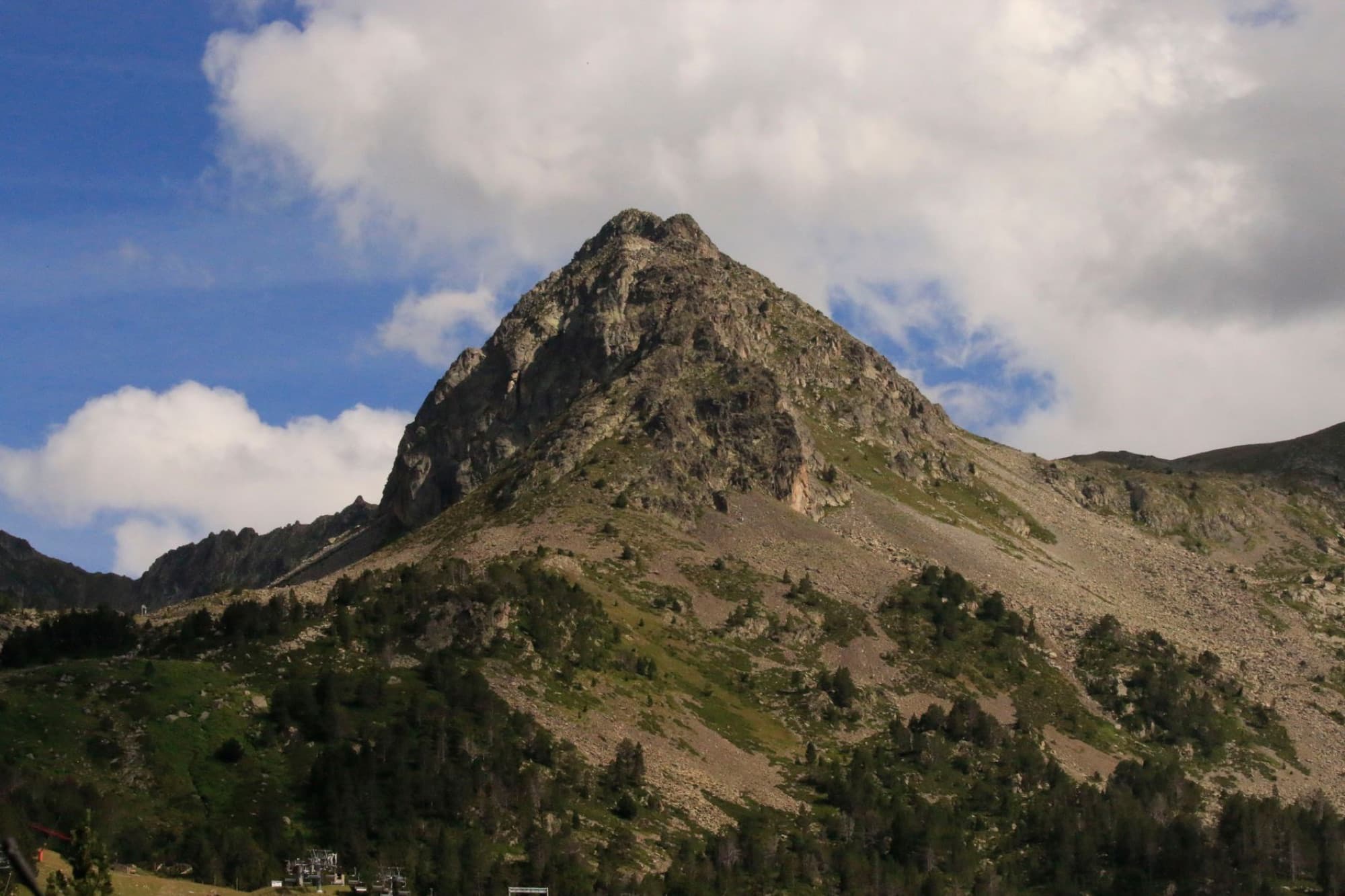 Breathtaking view of a rugged mountain peak in Ordino, Andorra, under a vivid blue sky, perfect for nature lovers and hikers.
