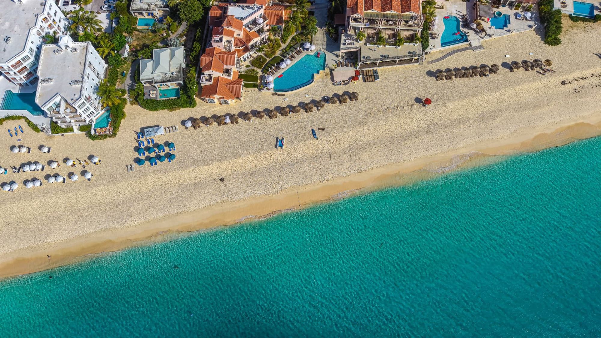 Stunning aerial view of a sandy beach and luxury resort in Anguilla with turquoise waters.