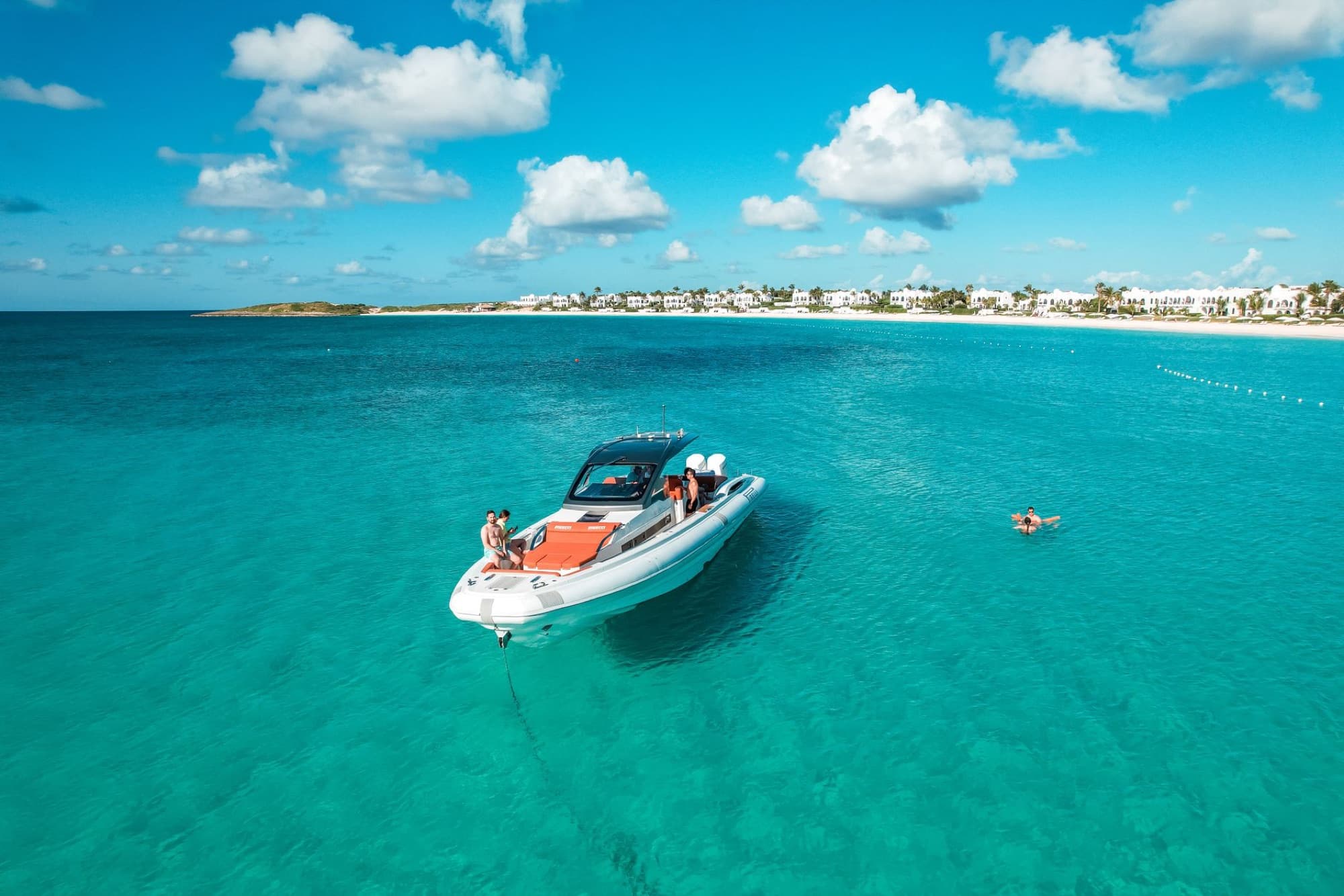 Aerial view of a motorboat in clear turquoise waters near a tropical beach, ideal for leisure and travel.