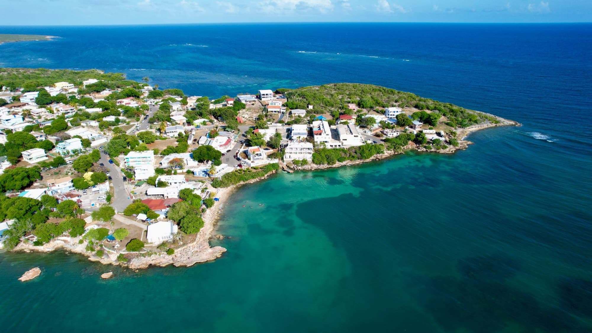 Explore a picturesque coastal town surrounded by turquoise waters in this stunning aerial view.