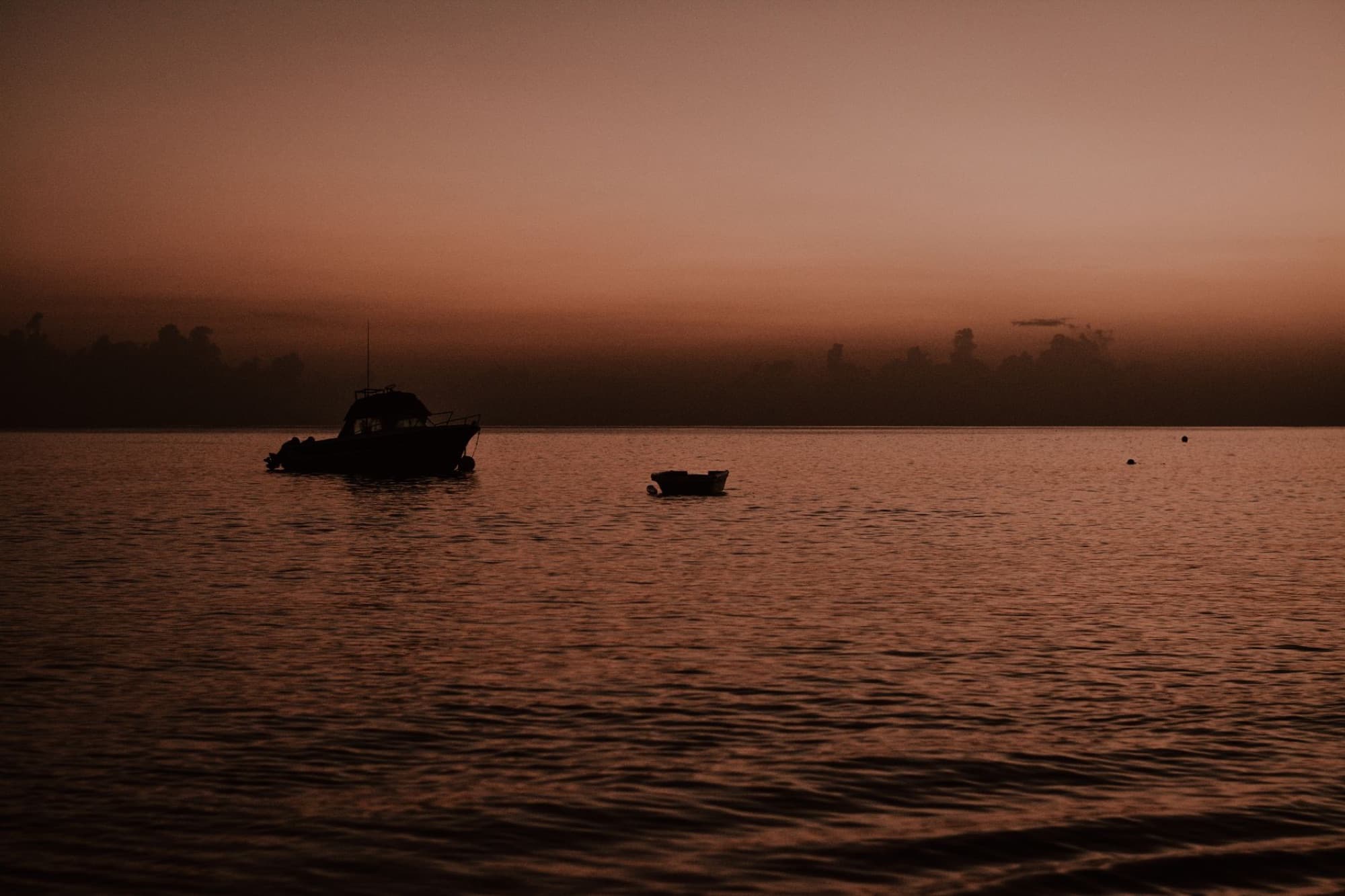 Silhouette of boats at sunset on the tranquil sea in Antigua and Barbuda.