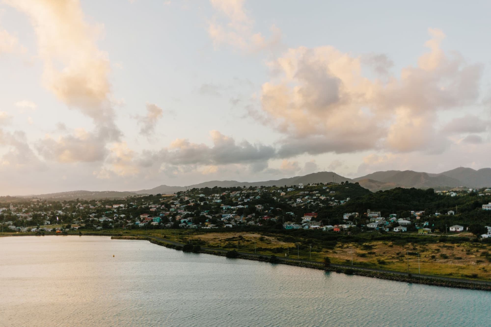 A picturesque aerial view of a coastal town with scattered clouds at sunset, capturing serene beauty.