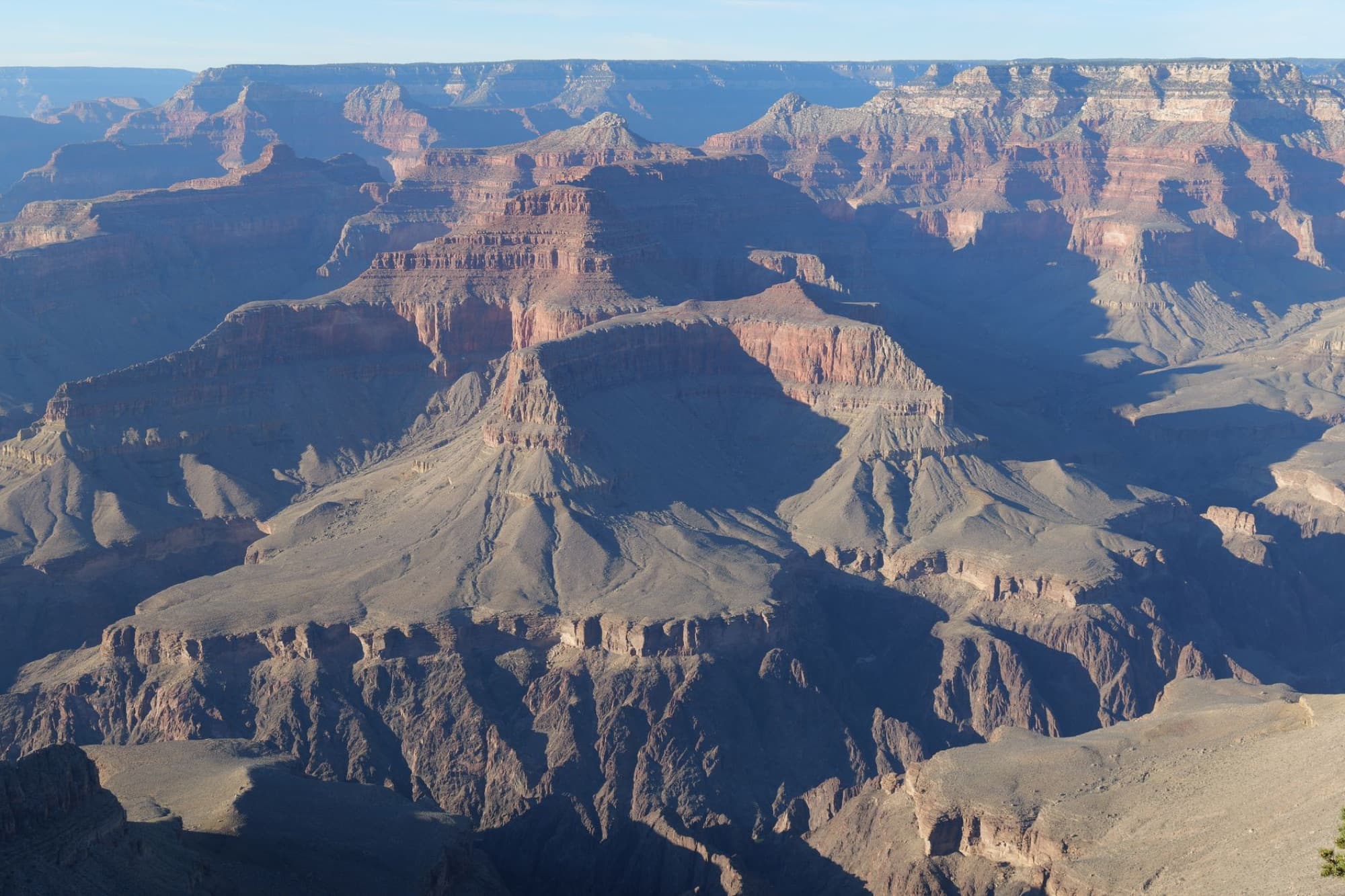 A stunning aerial view of the Grand Canyon showcasing its majestic cliffs, layers, and sunlight.