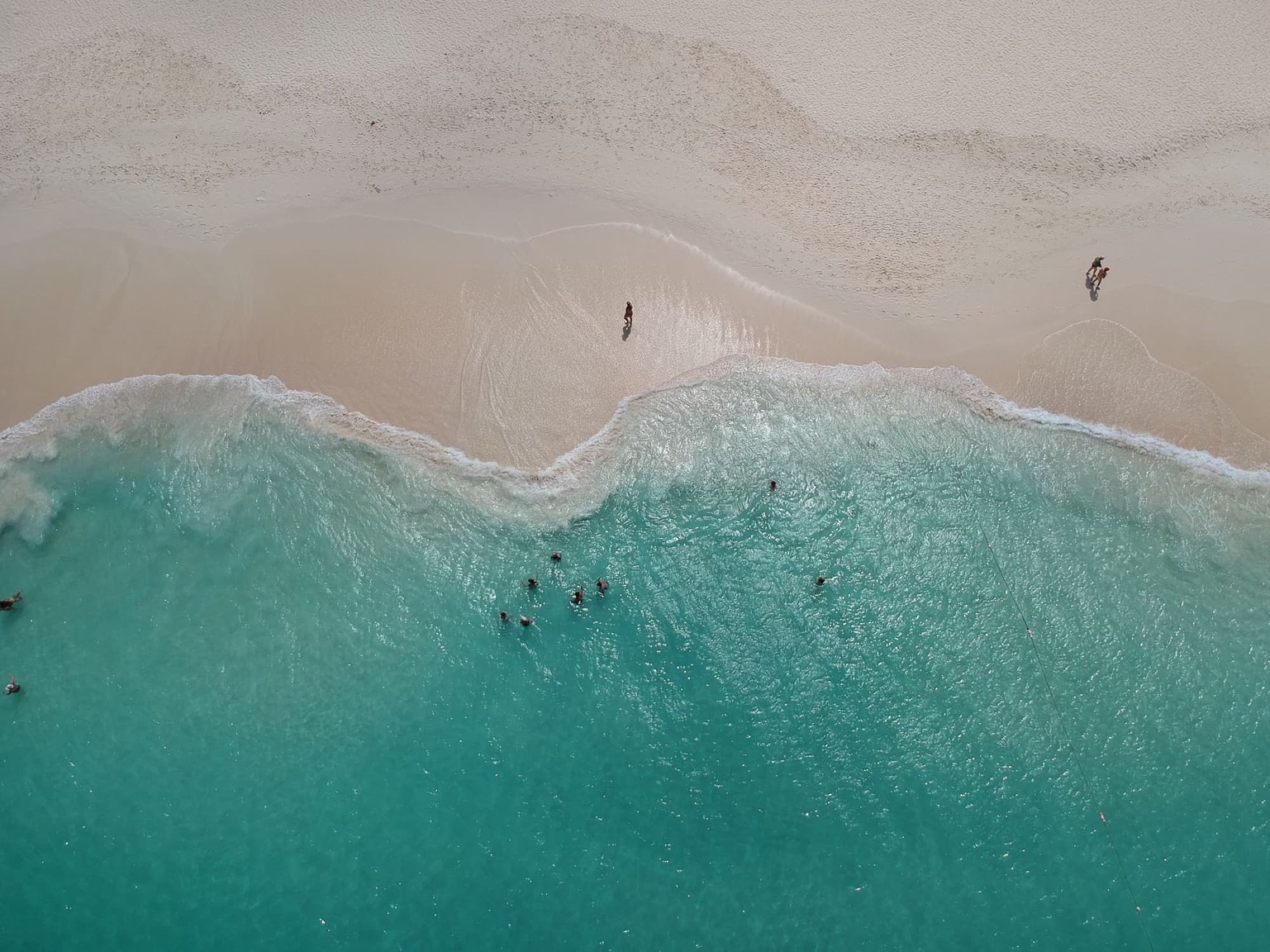 Stunning aerial view of turquoise waters meeting the sandy shore in Aruba, perfect beach escape.