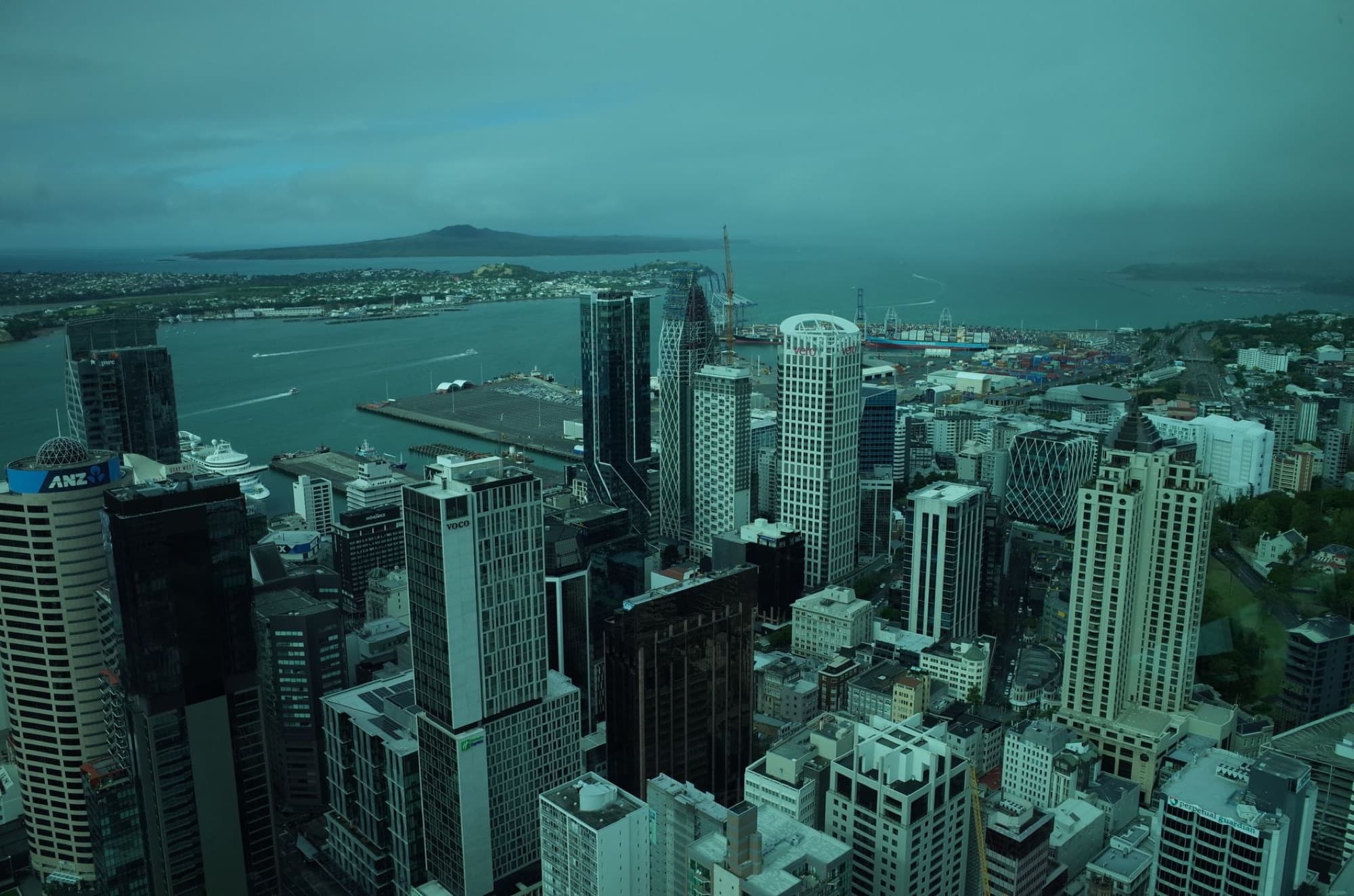 Stunning aerial view of Auckland cityscape showcasing skyline and waterfront on a cloudy day.