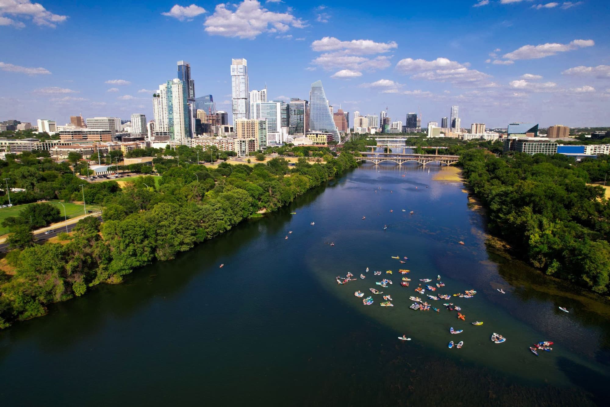 Aerial shot of Austin, Texas skyline with kayaks on the Colorado River on a sunny day.