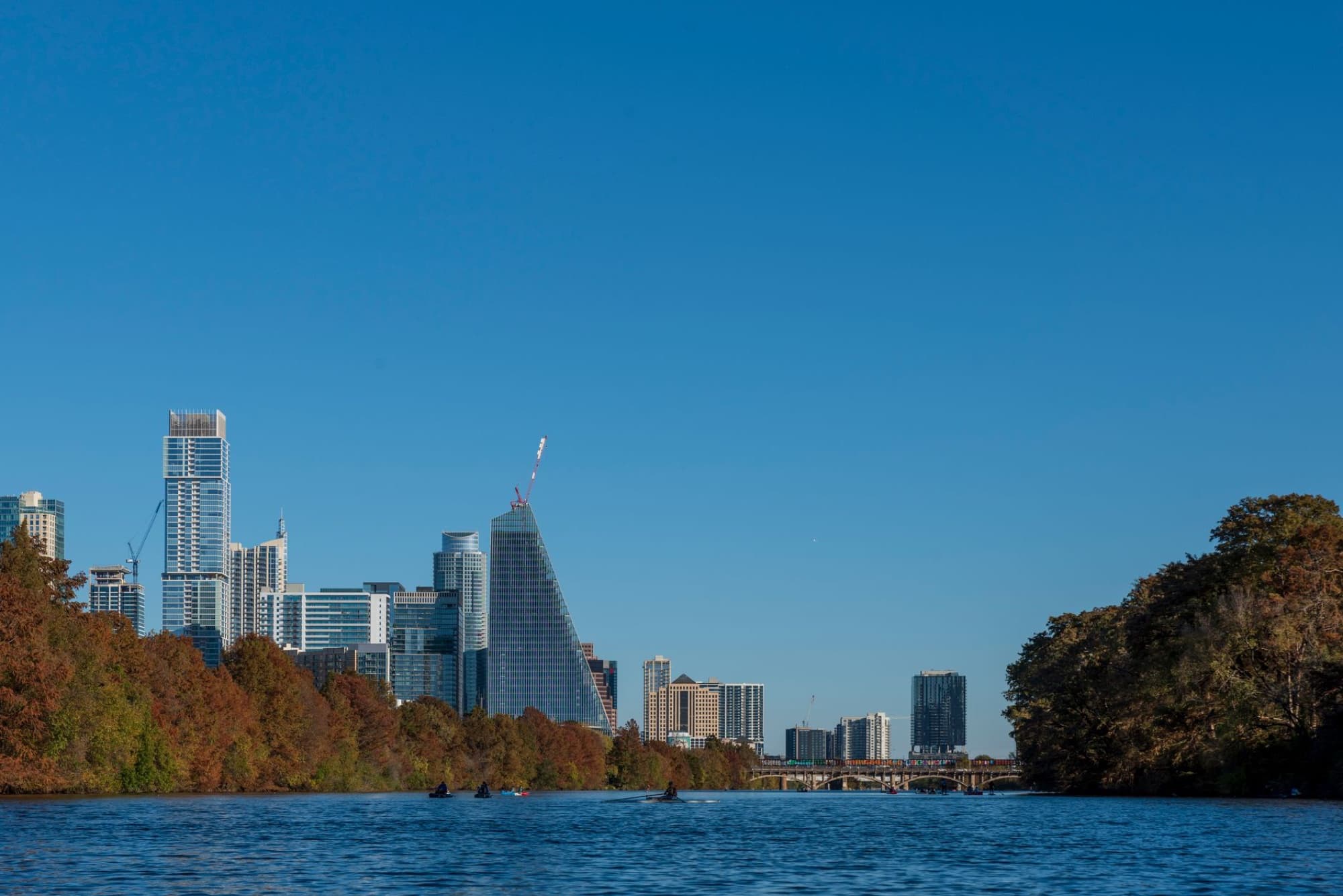 Beautiful view of the Austin skyline with skyscrapers reflecting on the river under a clear blue sky.
