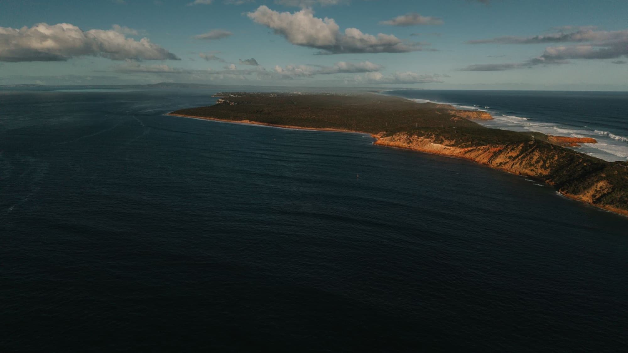 A breathtaking aerial view of the rugged coastline of Portsea, Victoria, Australia, bathed in sunlight.