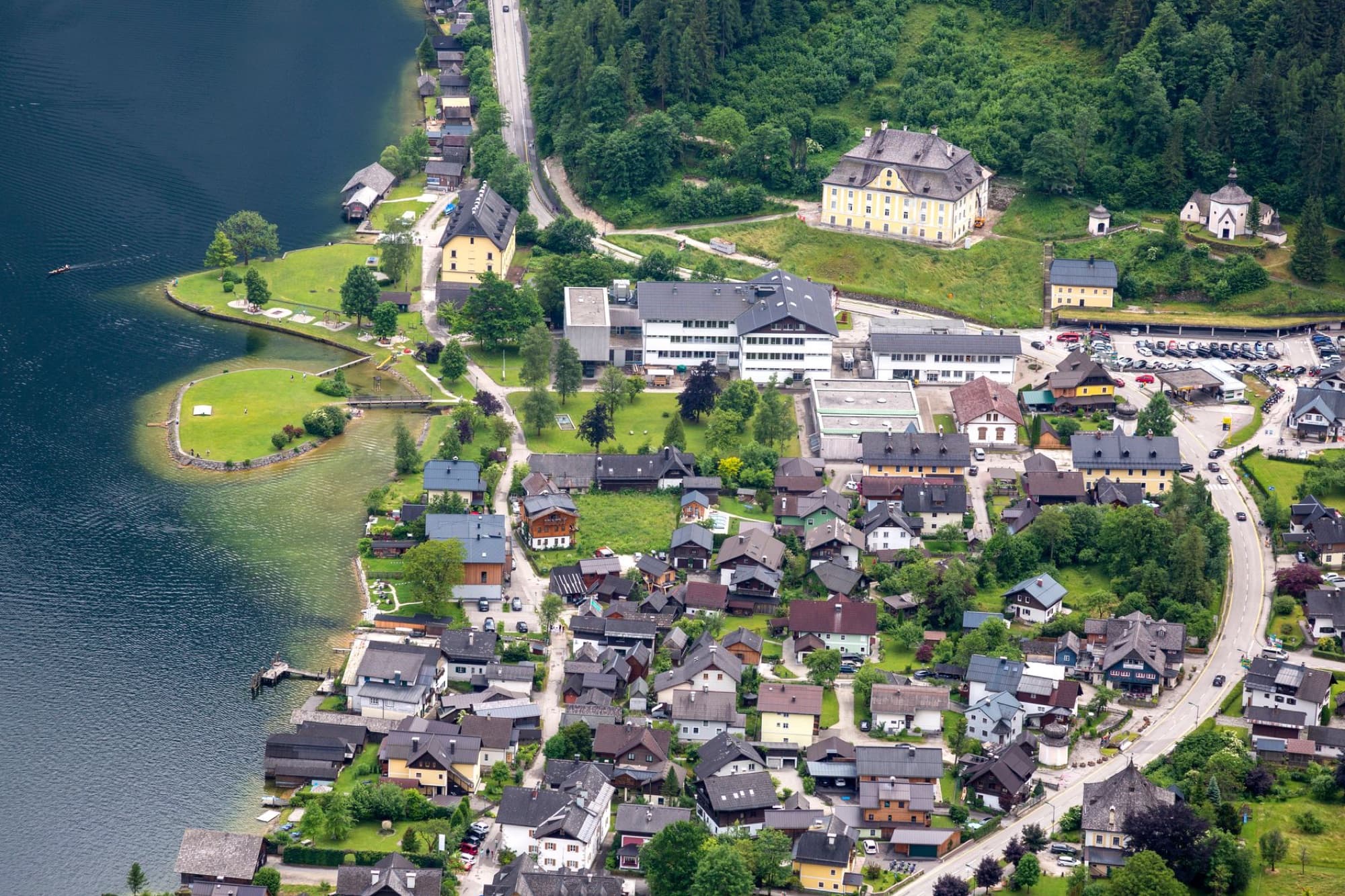 Aerial view of a charming lakeside town in Austria, surrounded by lush greenery and pristine waters.
