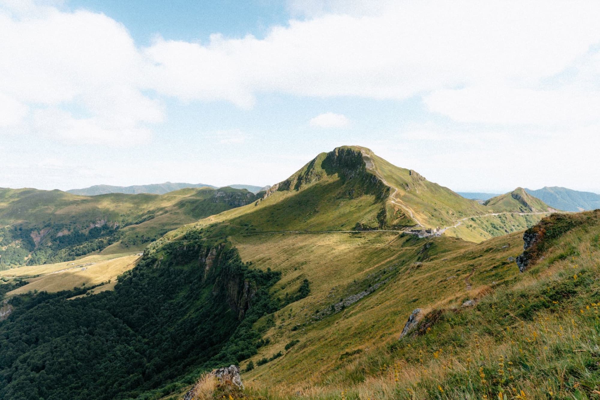 Breathtaking view of the lush green mountains in Auvergne-Rhône-Alpes, France under a clear summer sky.