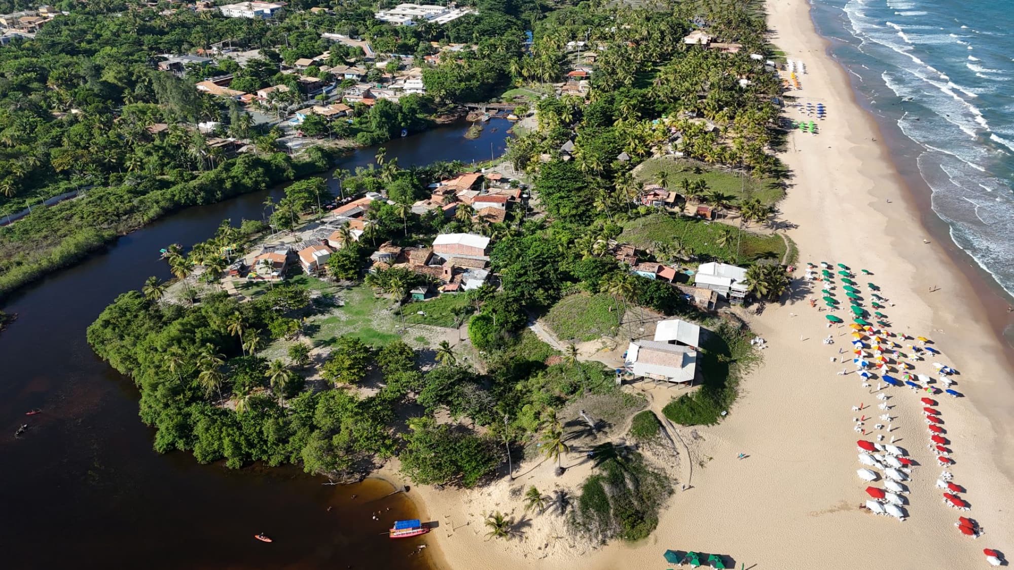 Explore the stunning aerial view of Imbassaí Beach, Bahia, showcasing sandy shores and vibrant umbrellas.