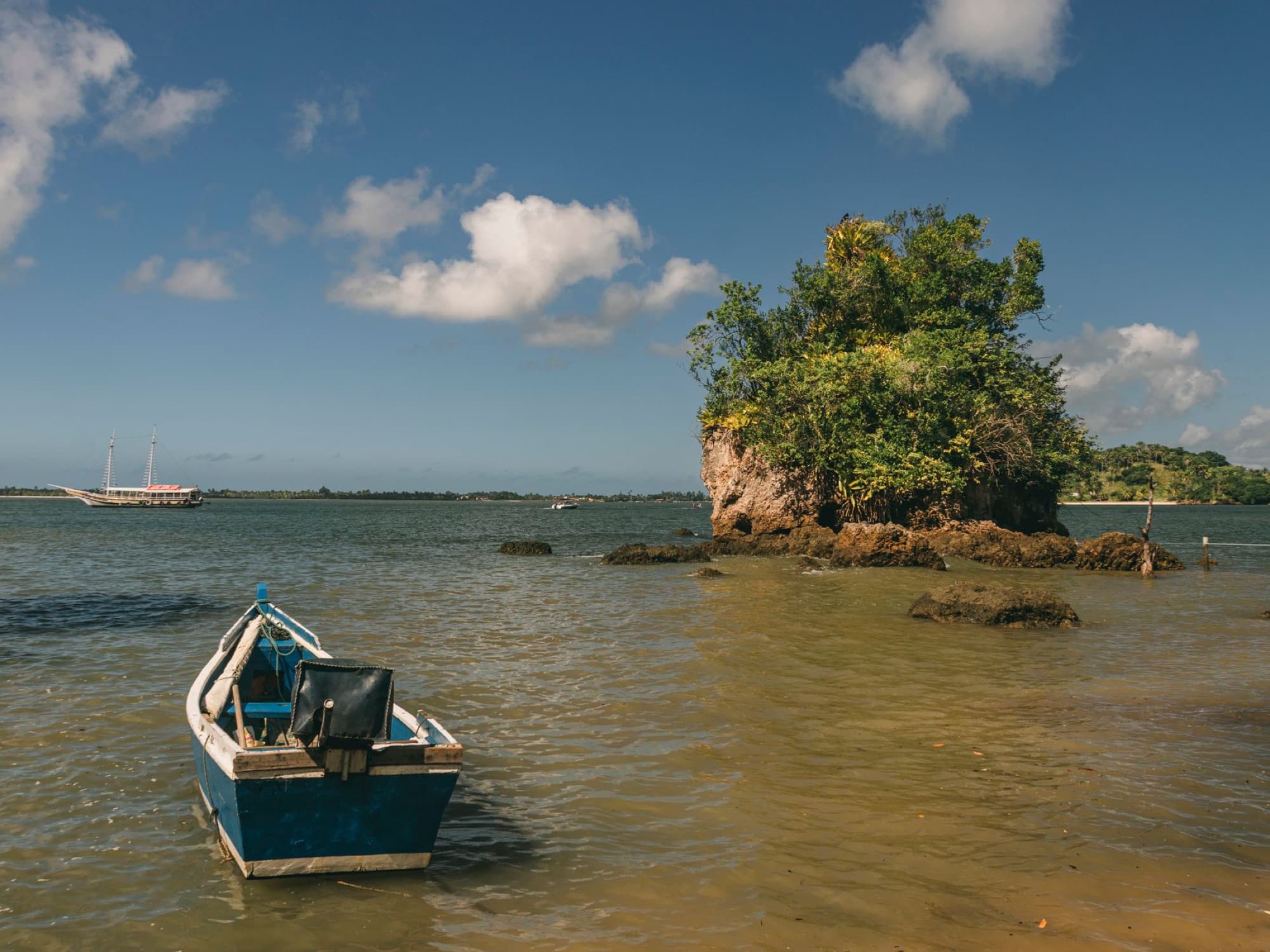 Tranquil beach scene with a boat and rock formation in Barra Grande, Bahia, Brazil.
