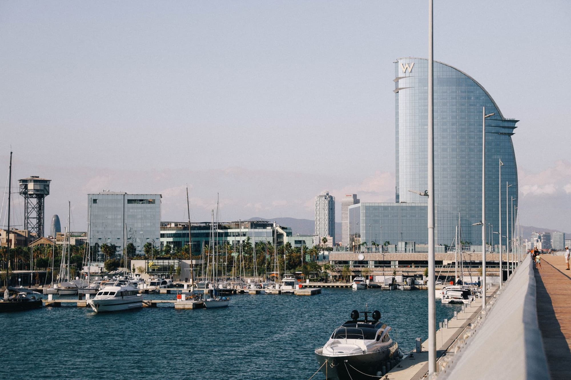 Modern architecture and boats in Barcelona's scenic harbor, with iconic skyline views.