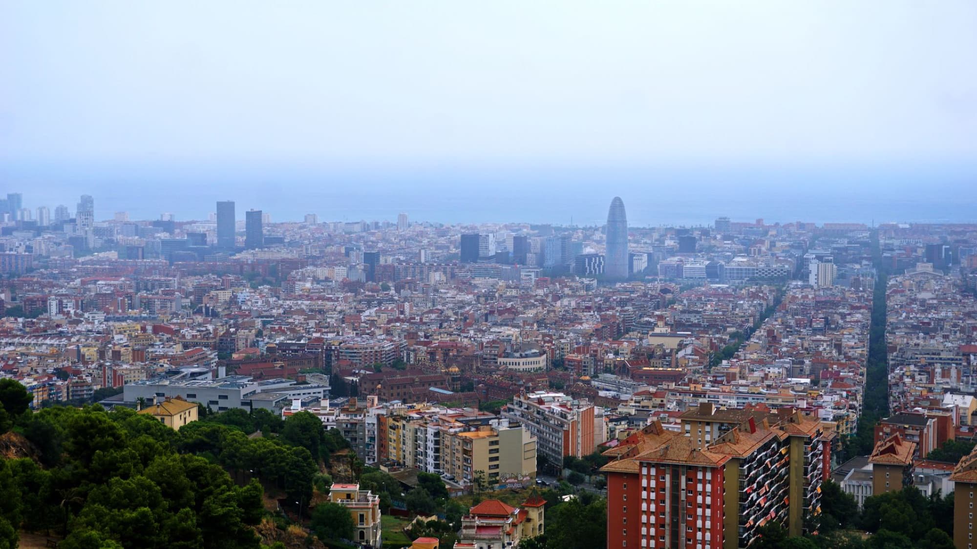 A breathtaking aerial view of Barcelona's cityscape featuring the skyline and Mediterranean Sea in the background.