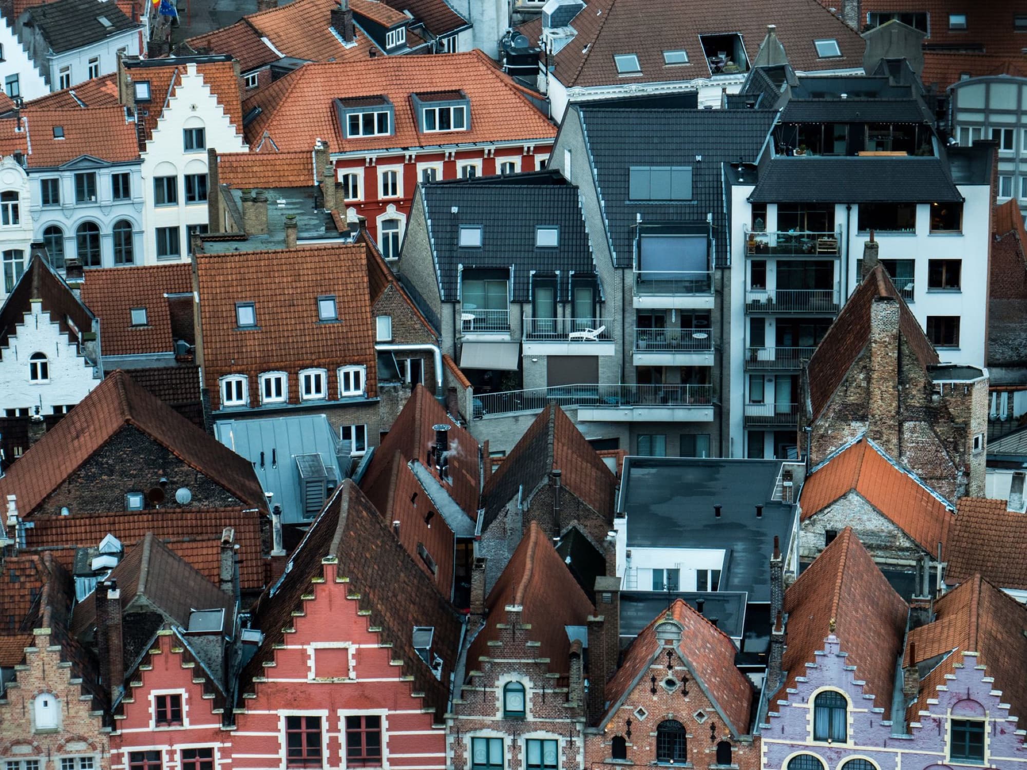 Aerial view of traditional and modern rooftops in Bruges, Belgium, showcasing the city's rich architectural diversity.
