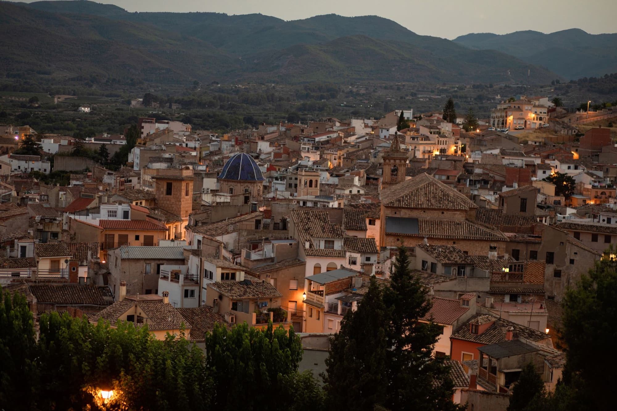 Aerial view of a charming old town at twilight with mountains in the background.