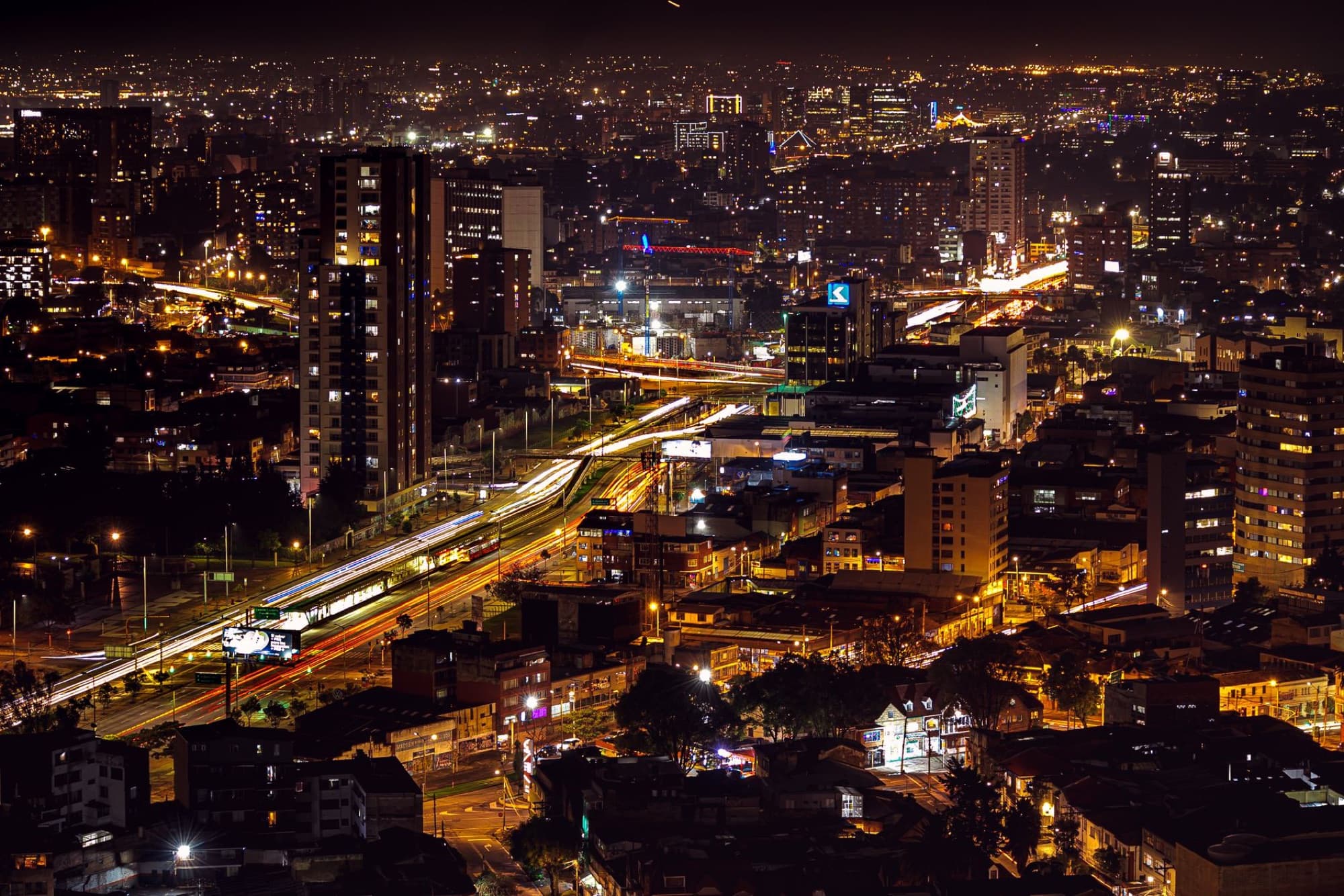 Stunning aerial view of Bogotá skyline at night, capturing city lights and urban vibrancy.
