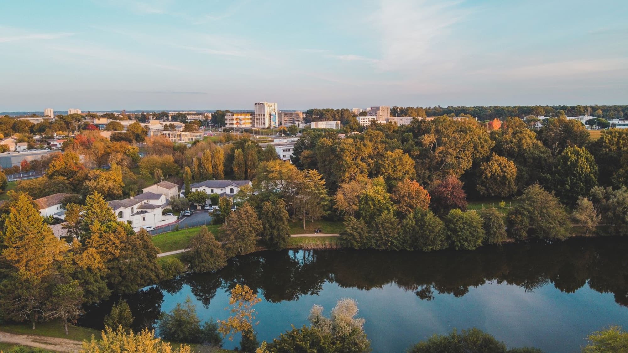 Scenic aerial view of Bordeaux, France in the vibrant autumn season with a lake and lush trees.