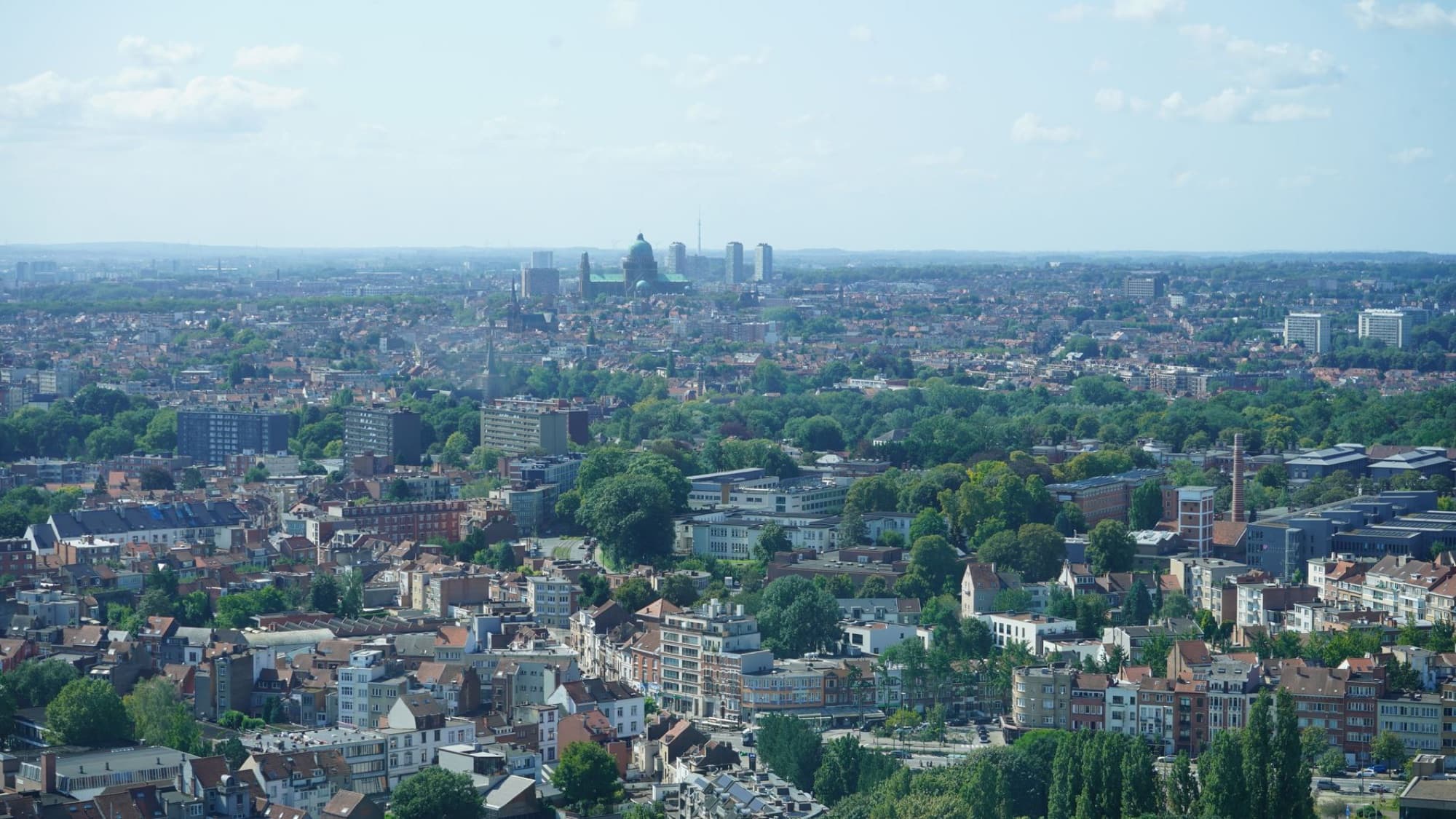 Aerial view of Brussels city with iconic landmarks and lush greenery.