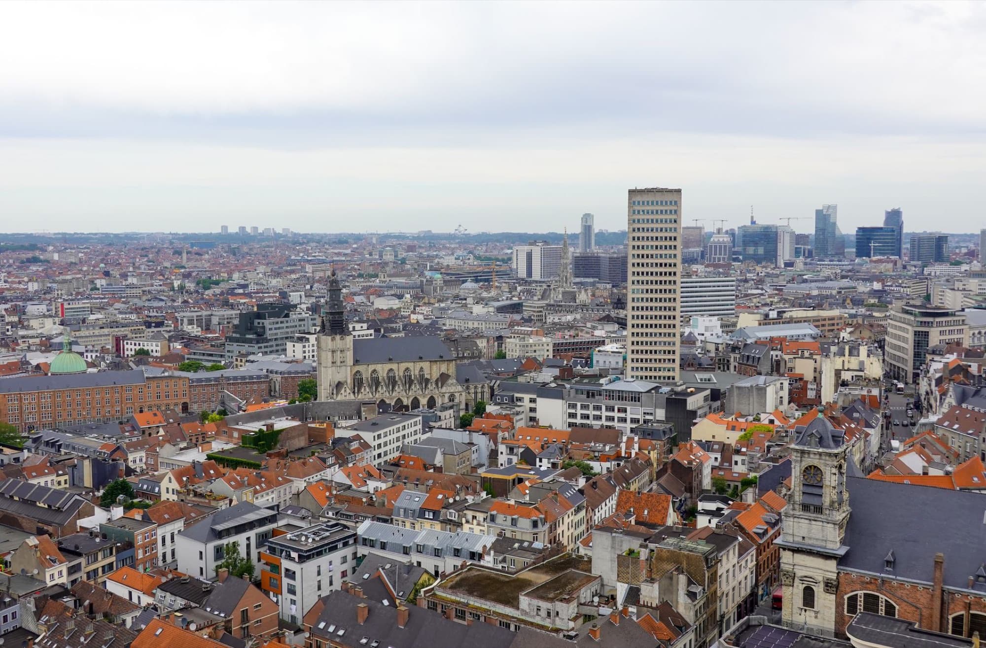 Aerial view of Brussels highlighting historic architecture and modern skyline under a cloudy sky.