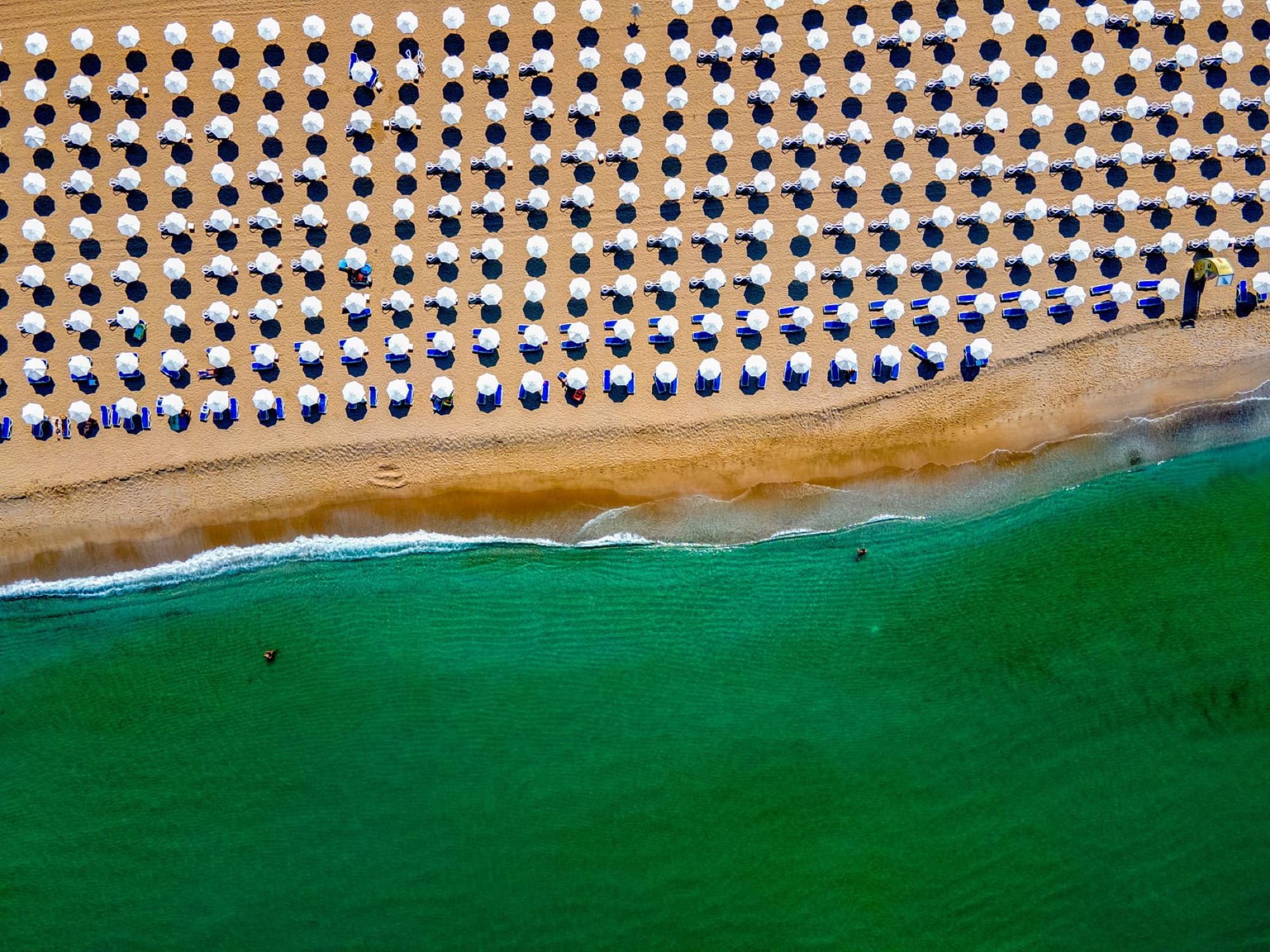 Vibrant aerial view of beach umbrellas lined up on Sozopol beach in Bulgaria's summer coast.