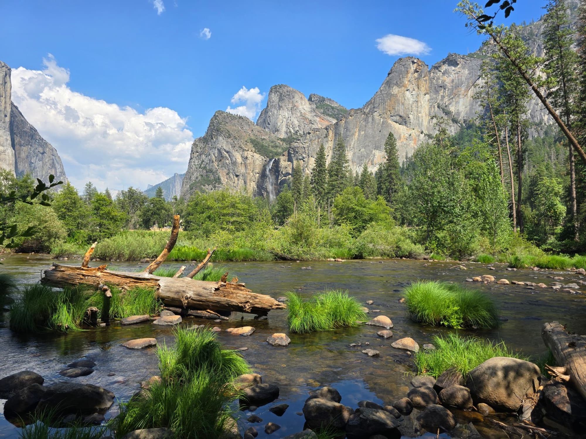 Breathtaking landscape of Yosemite Valley with vibrant greenery, towering cliffs, and a calm river.