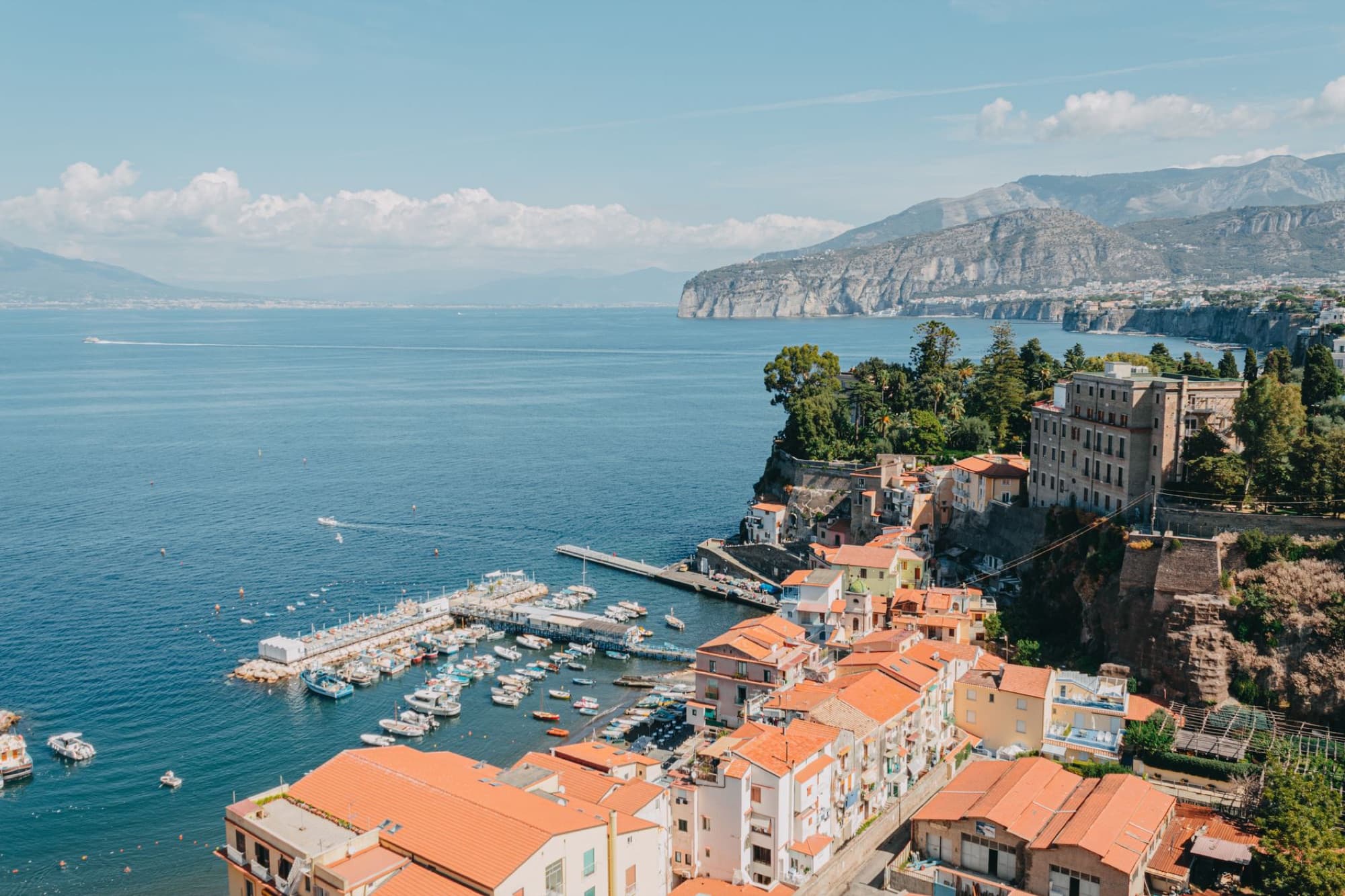 Aerial view of Sorrento's stunning coastline and harbor with vibrant buildings and boats in Campania, Italy.