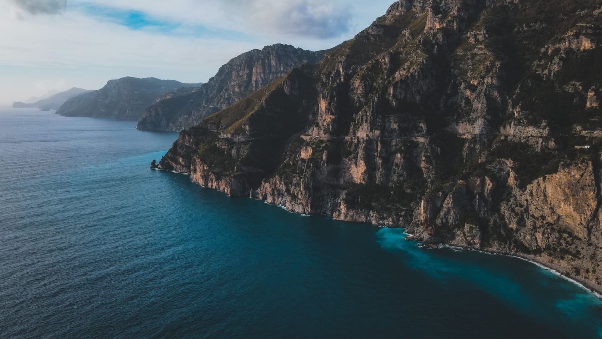 Captivating aerial view of the rocky coastline of Positano, Campania, Italy against the shimmering azure sea.
