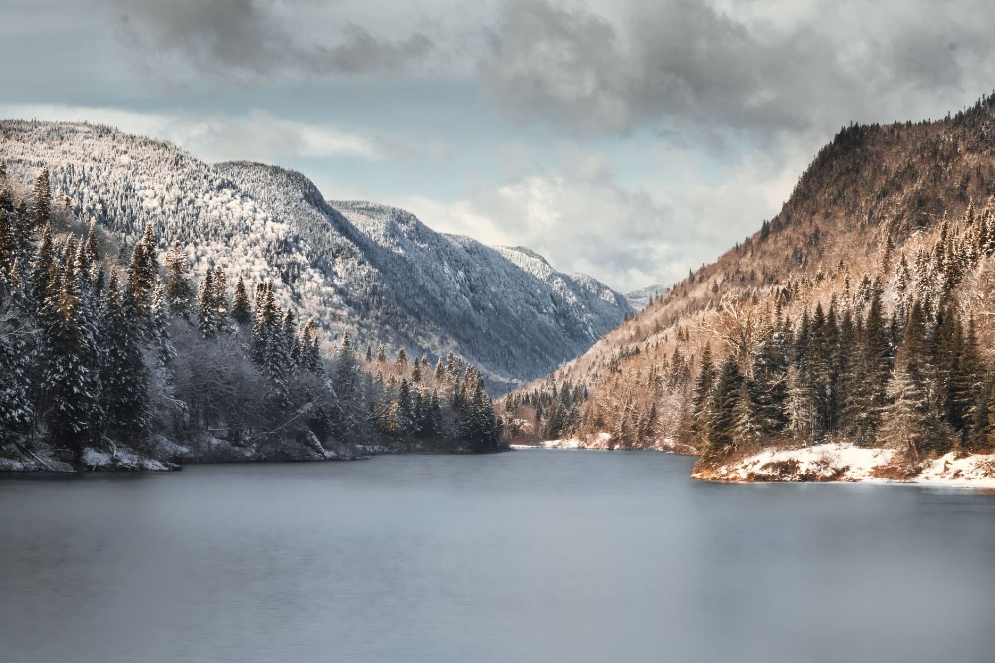 Snow-covered mountains and calm lake in Quebec's scenic winter landscape.