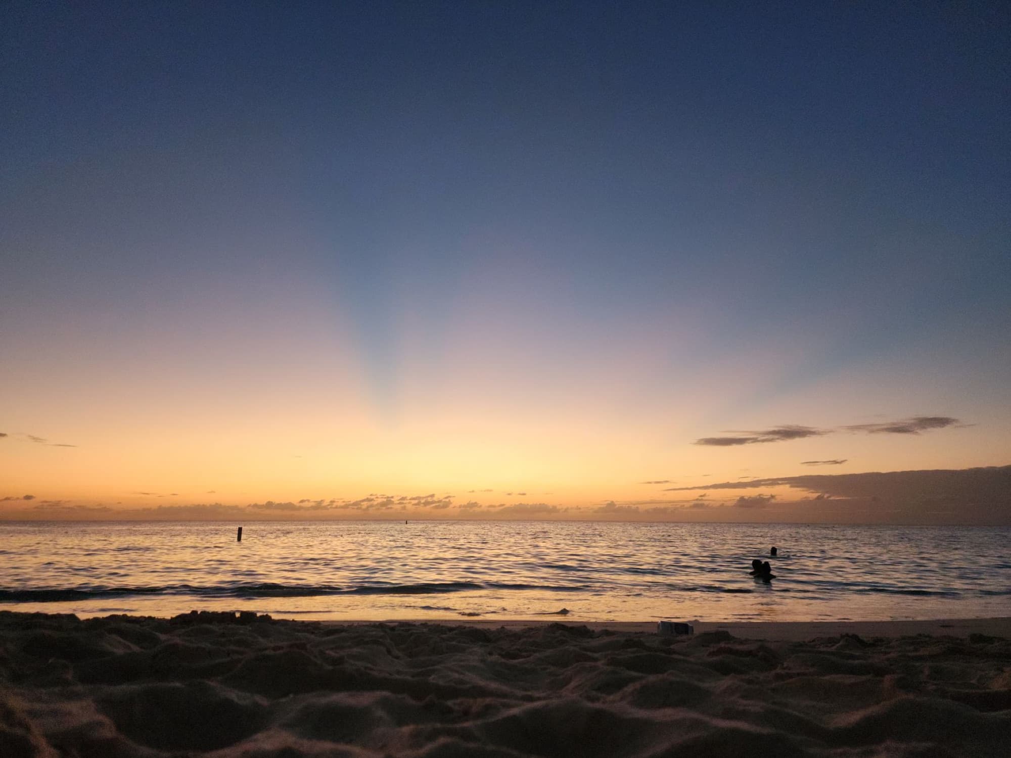 Experience the tranquil beauty of a Cayman Islands beach at sunset with golden skies and calm waters.