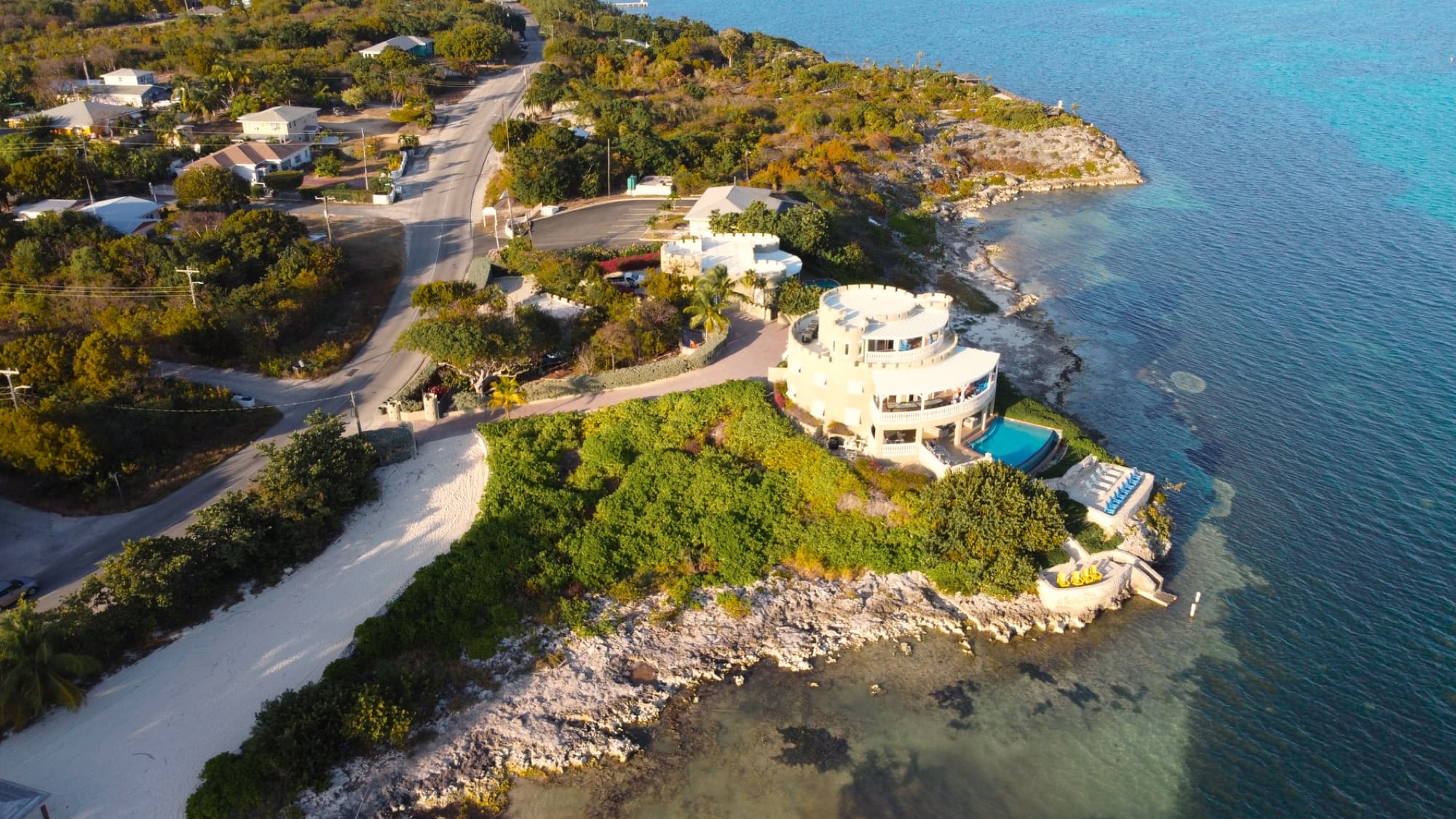 Stunning aerial view of a luxury villa on the coast of the Cayman Islands, surrounded by crystal-clear waters.