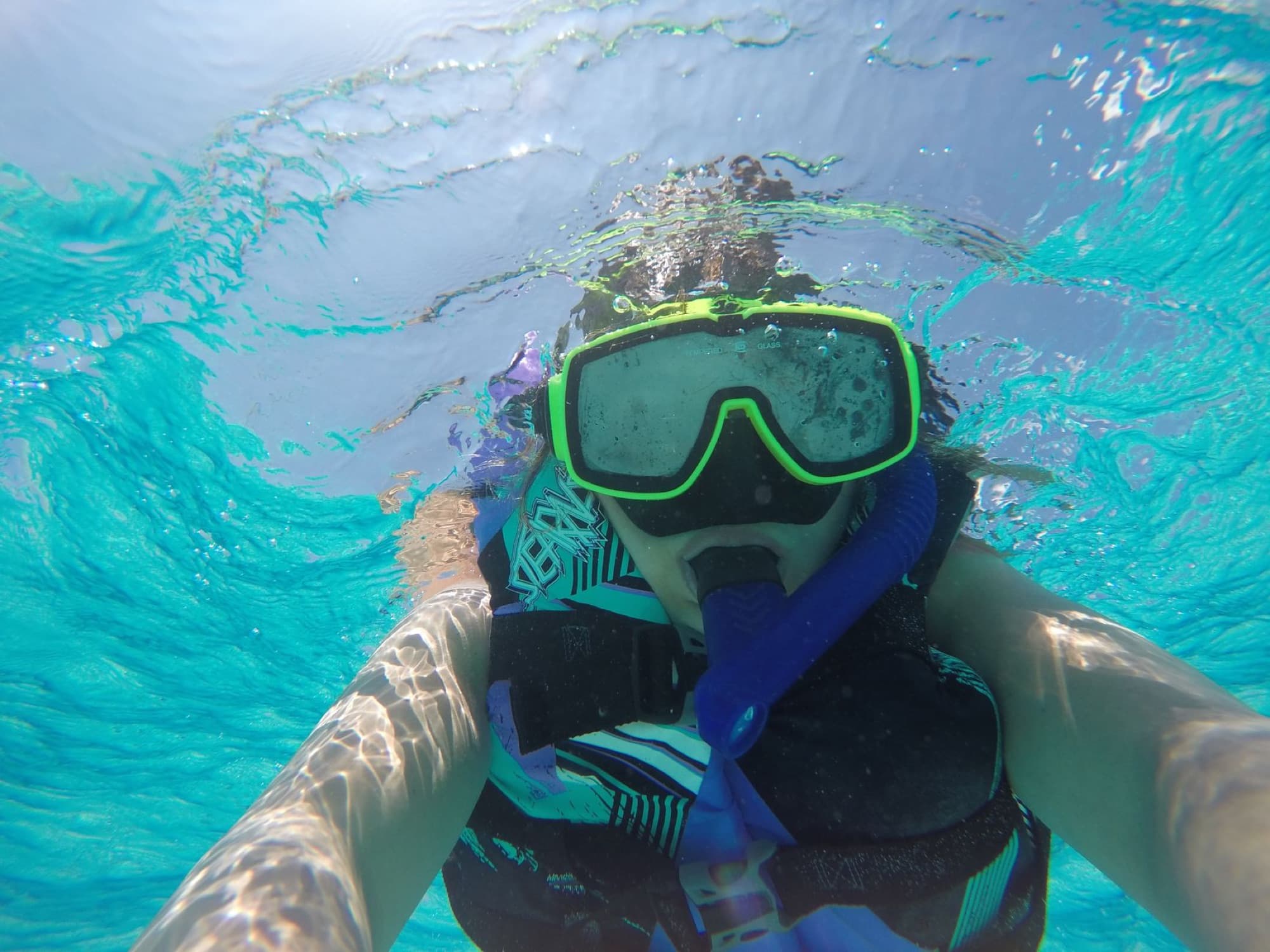Snorkeler explores vibrant blue waters of Cayman Islands.