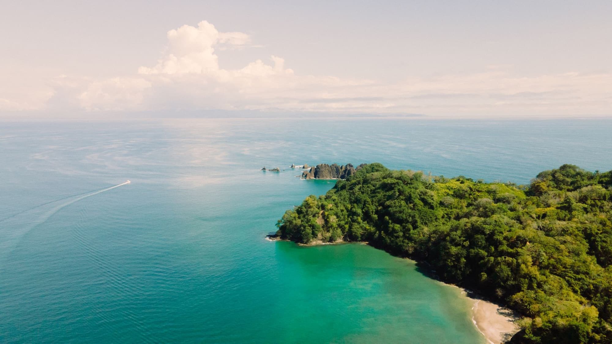 Stunning aerial shot of a tropical island surrounded by clear blue sea and lush green landscape.