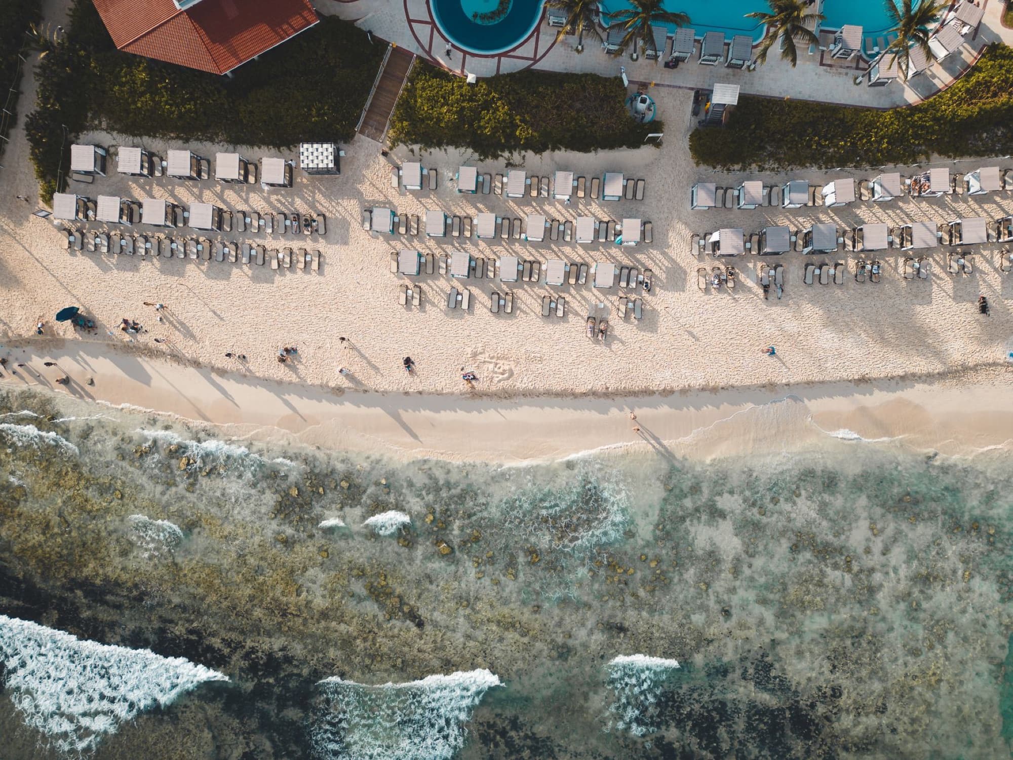 Aerial shot of a beachfront resort in Playa del Carmen, showing sun loungers, beach, and ocean.