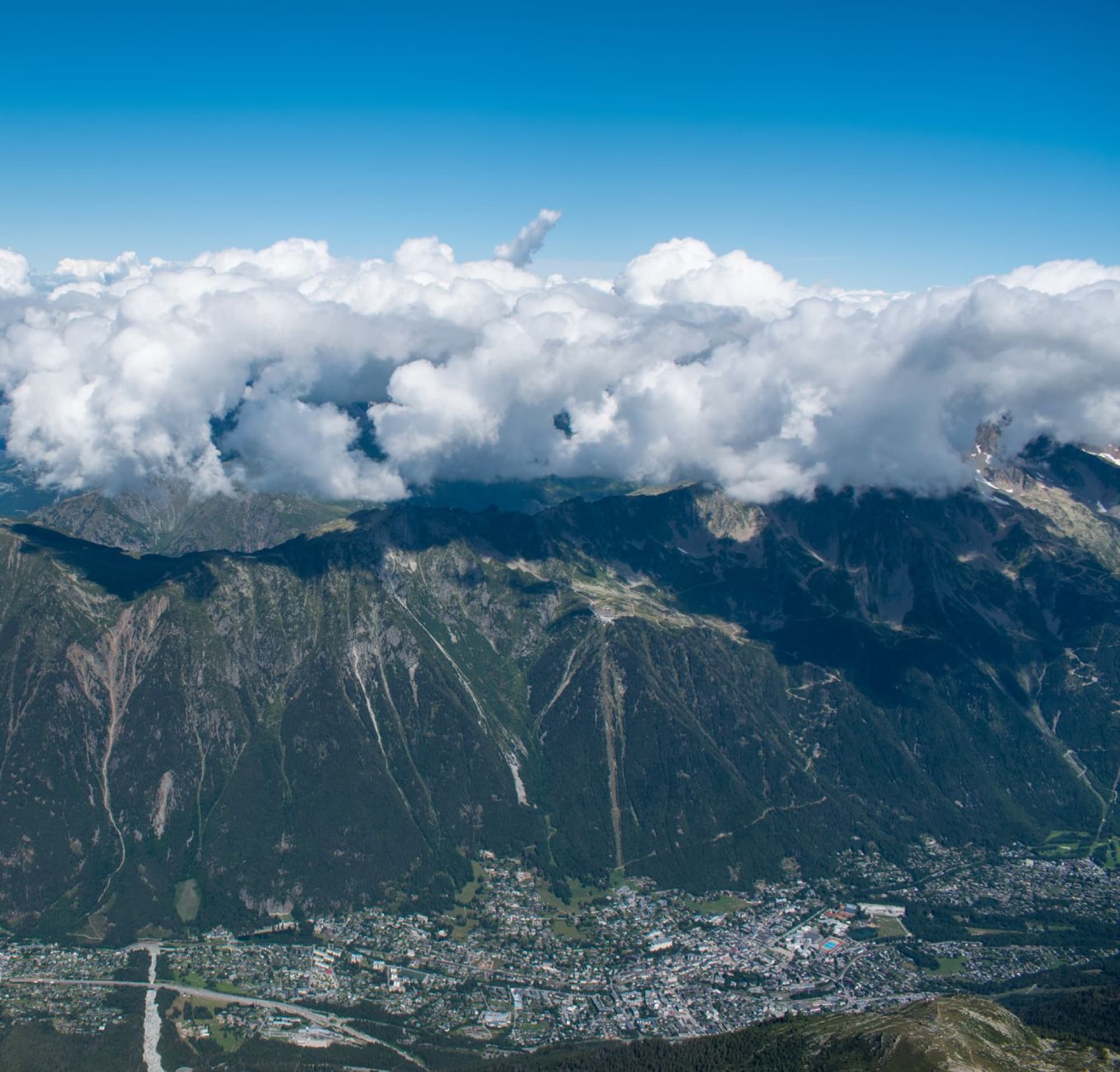 Breathtaking aerial view of Chamonix Valley and mountains under a vibrant blue sky with clouds.