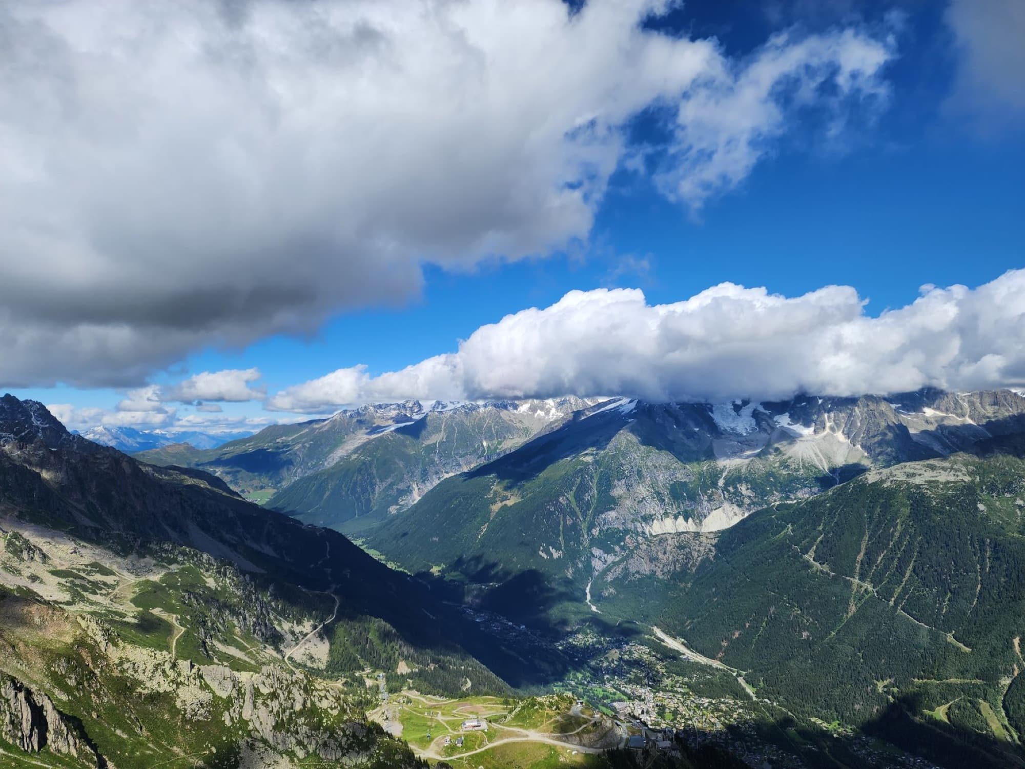 Stunning aerial view of Chamonix-Mont-Blanc with lush valleys and dramatic clouds.