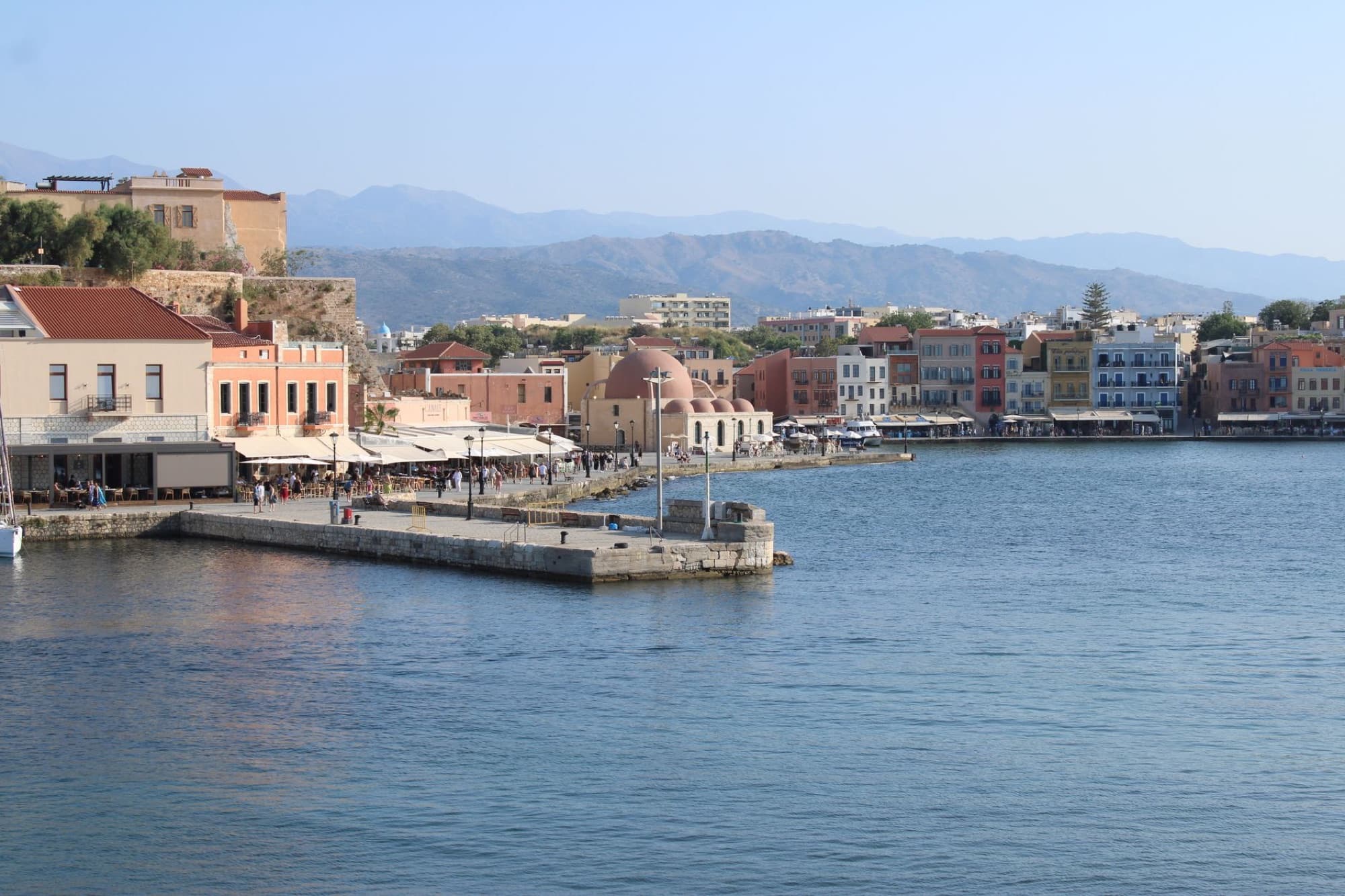 Scenic view of Chania harbor featuring traditional buildings and mountains in Greece.
