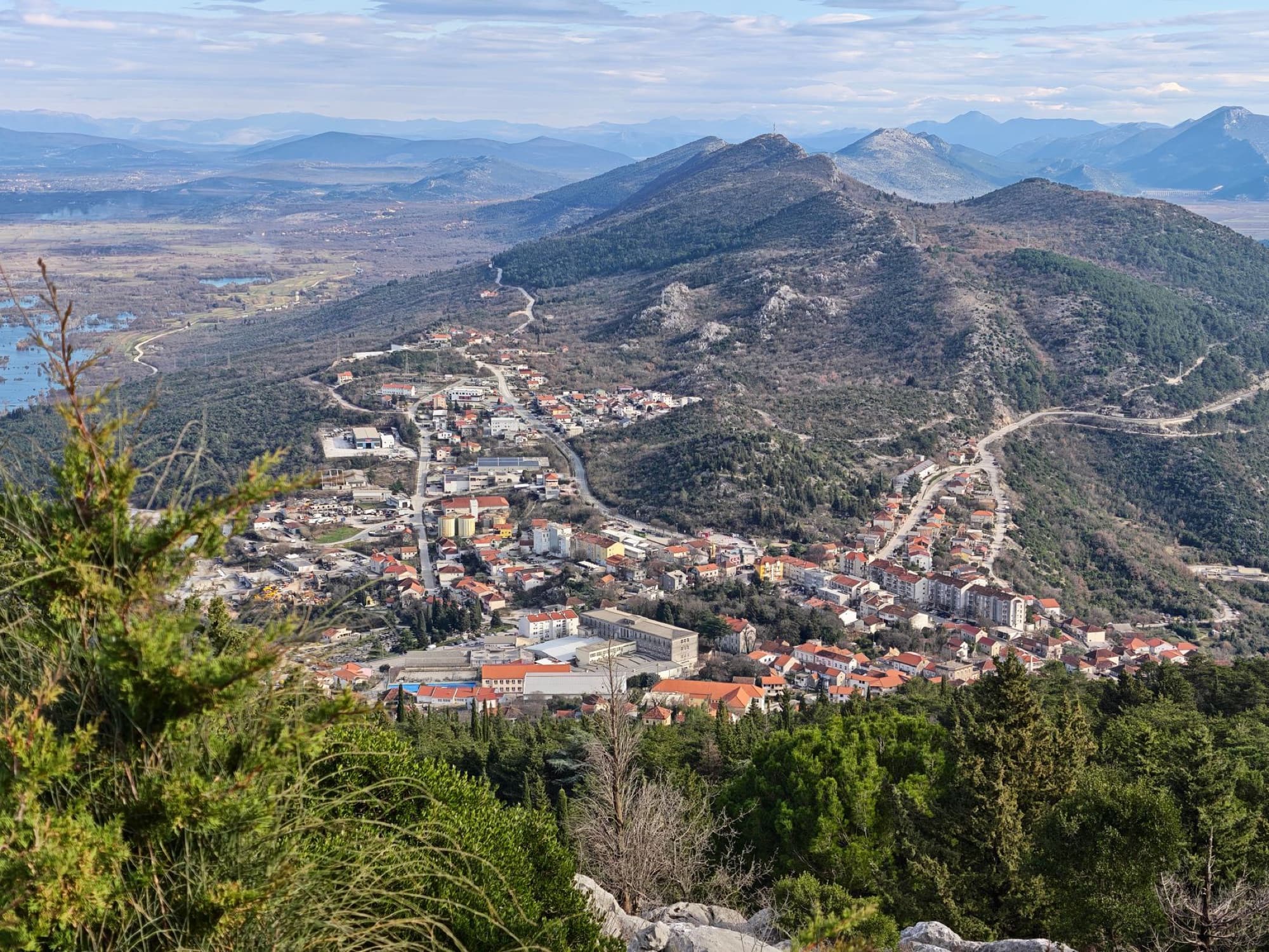 Breathtaking aerial view of a Croatian town nestled among lush hills and mountains, showcasing natural beauty.