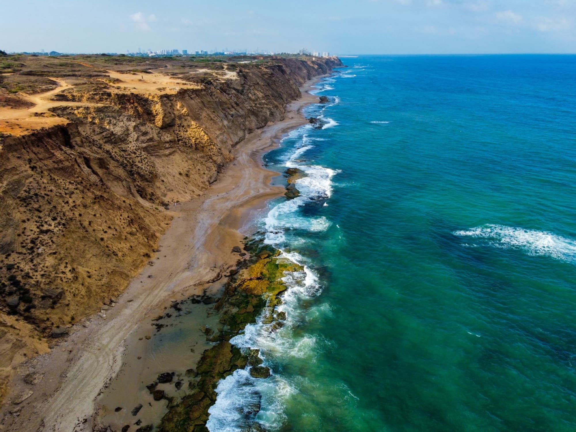 Aerial view of the stunning Arsuf coastline in Israel, showcasing dramatic cliffs and azure waves.