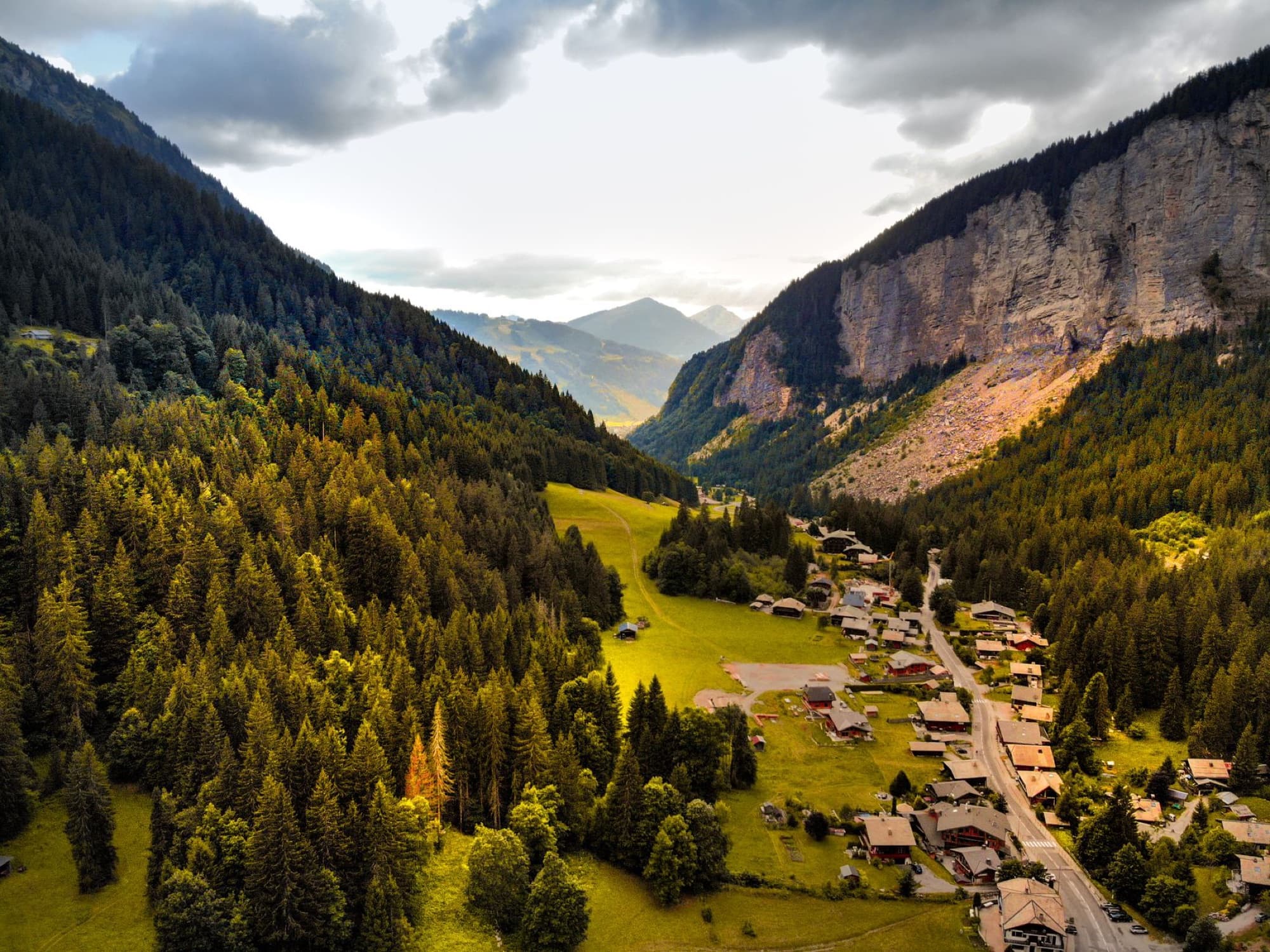 A breathtaking aerial view of a lush valley with a scenic village nestled between towering cliffs.