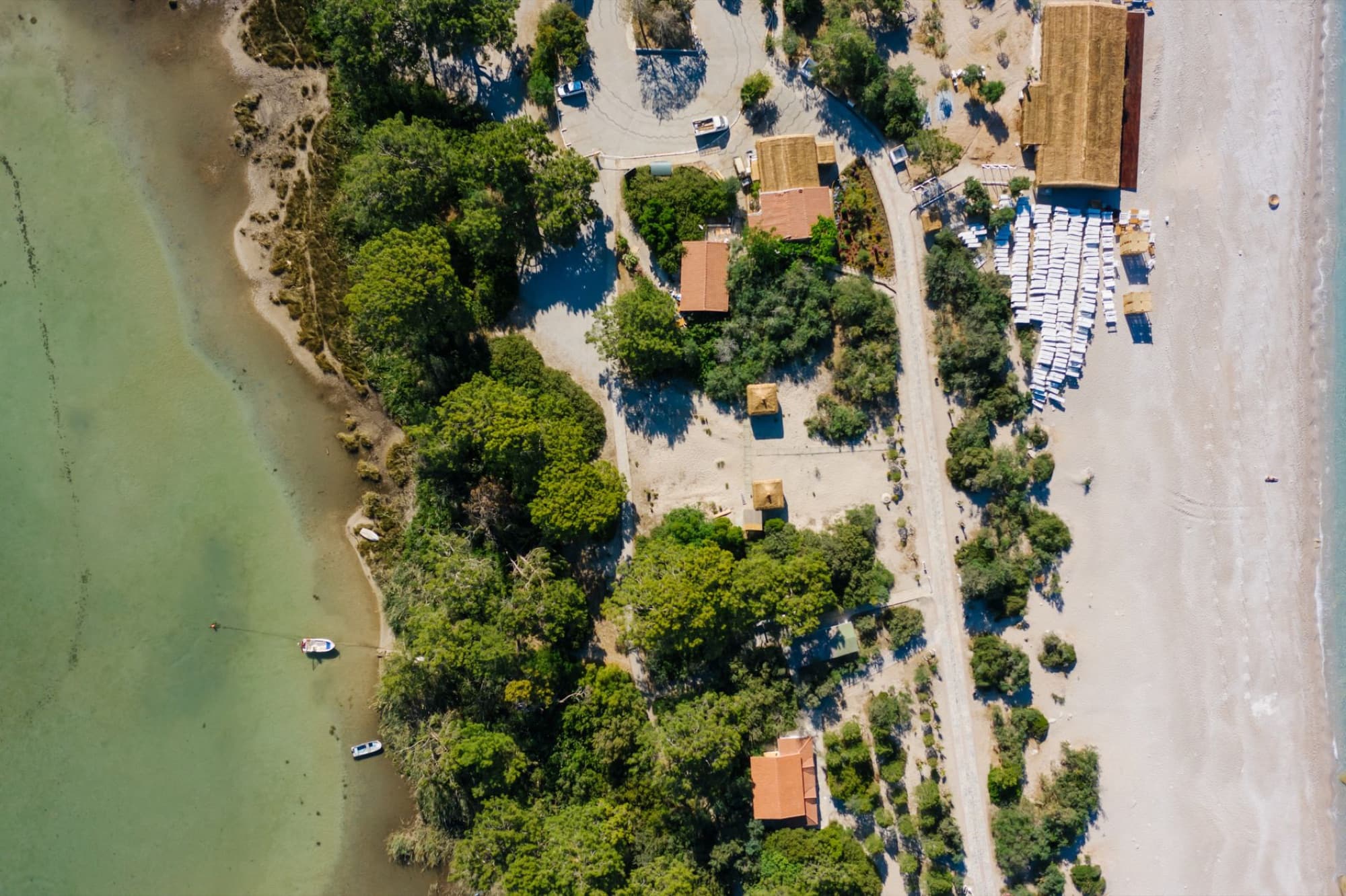A stunning aerial view of a secluded beach area with lush trees, clear waters, and sandy coastline.