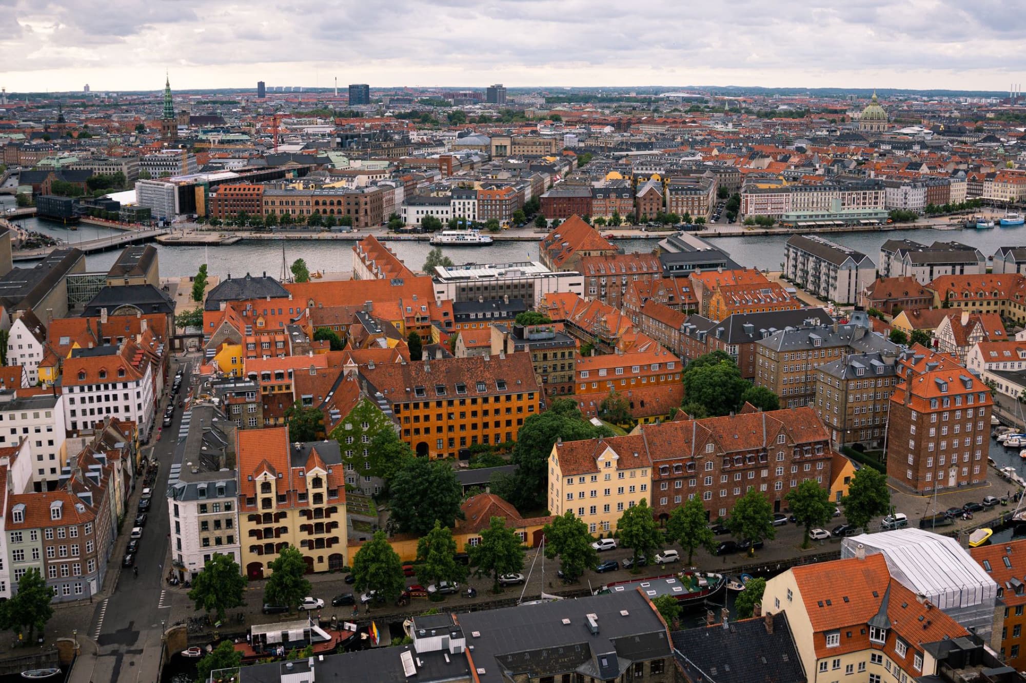 Scenic aerial view of Copenhagen's red rooftops and waterways, showcasing urban architecture.