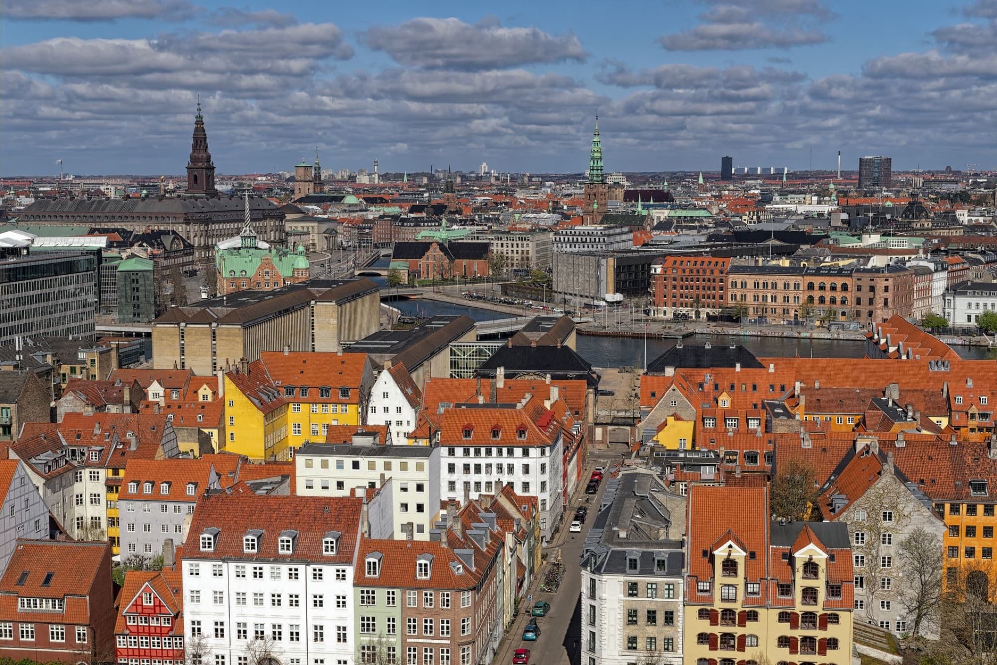Vibrant aerial view of Copenhagen with historic buildings and modern architecture under blue sky.