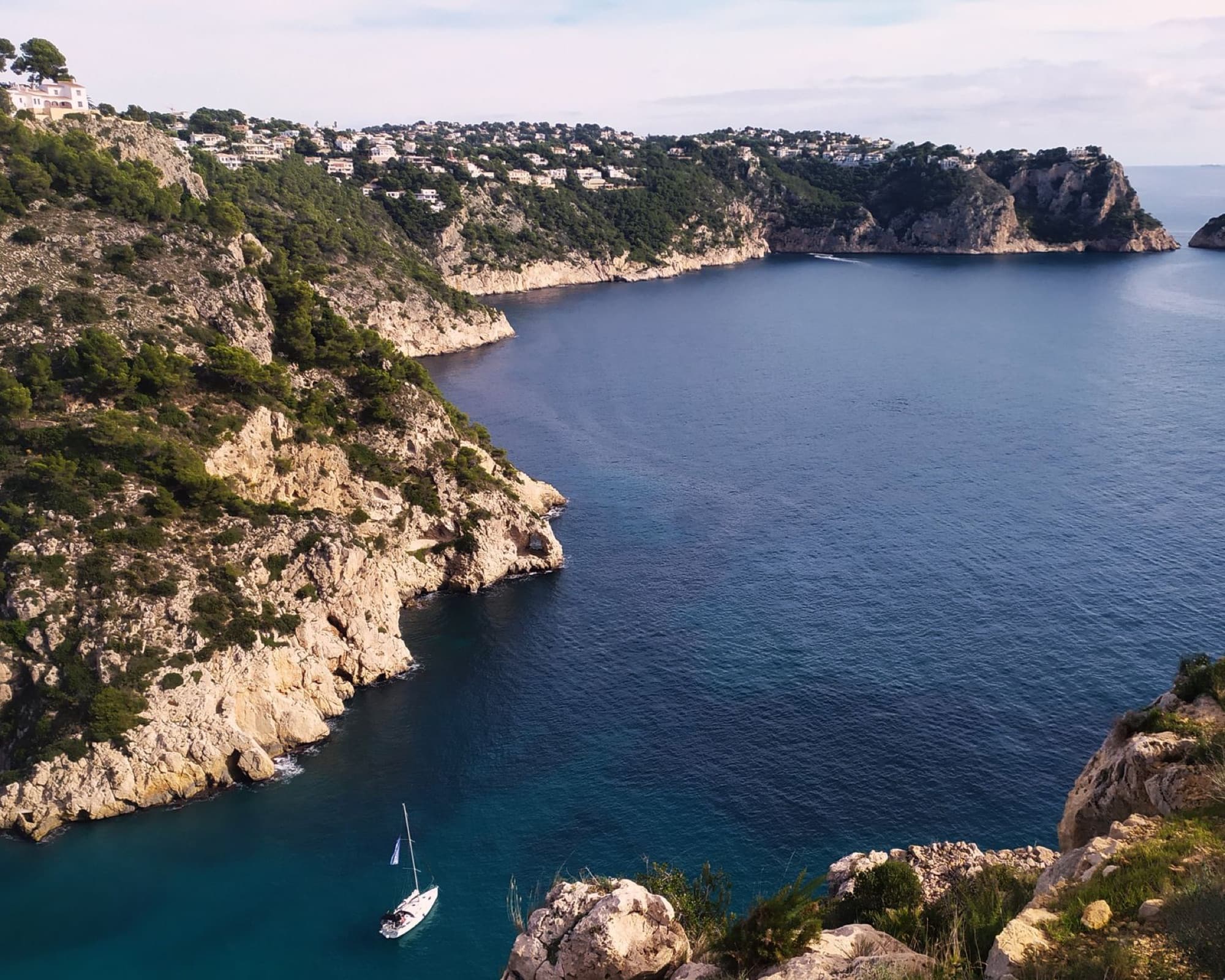 A stunning aerial view of the rocky coastline and tranquil waters of Jávea Bay, Costa Blanca, Spain.